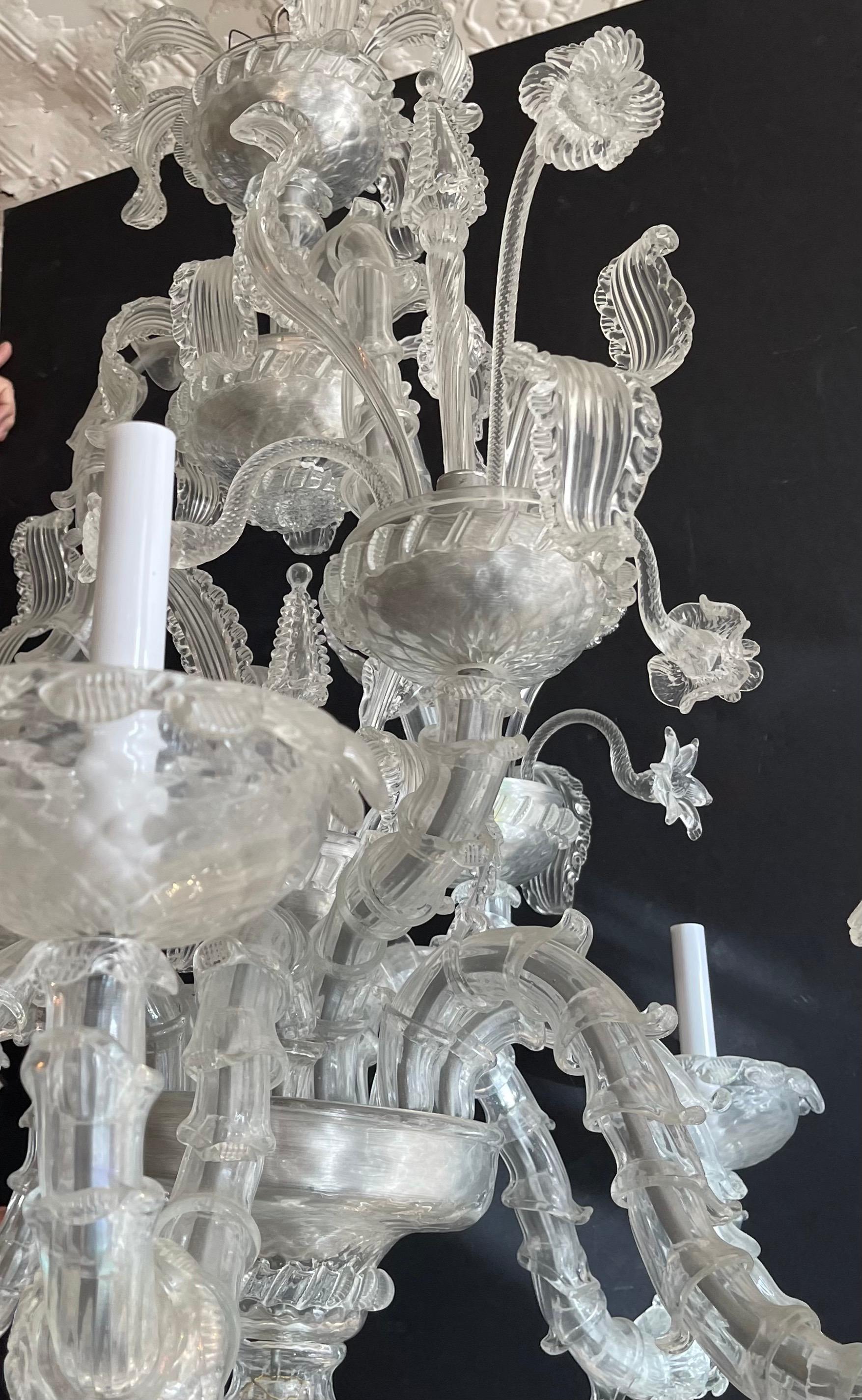 Un meraviglioso lampadario a due piani in vetro soffiato trasparente italiano della metà del secolo scorso, decorato con foglie e fiori che pendono dal piano superiore e con campanelle che scendono da ogni braccio.