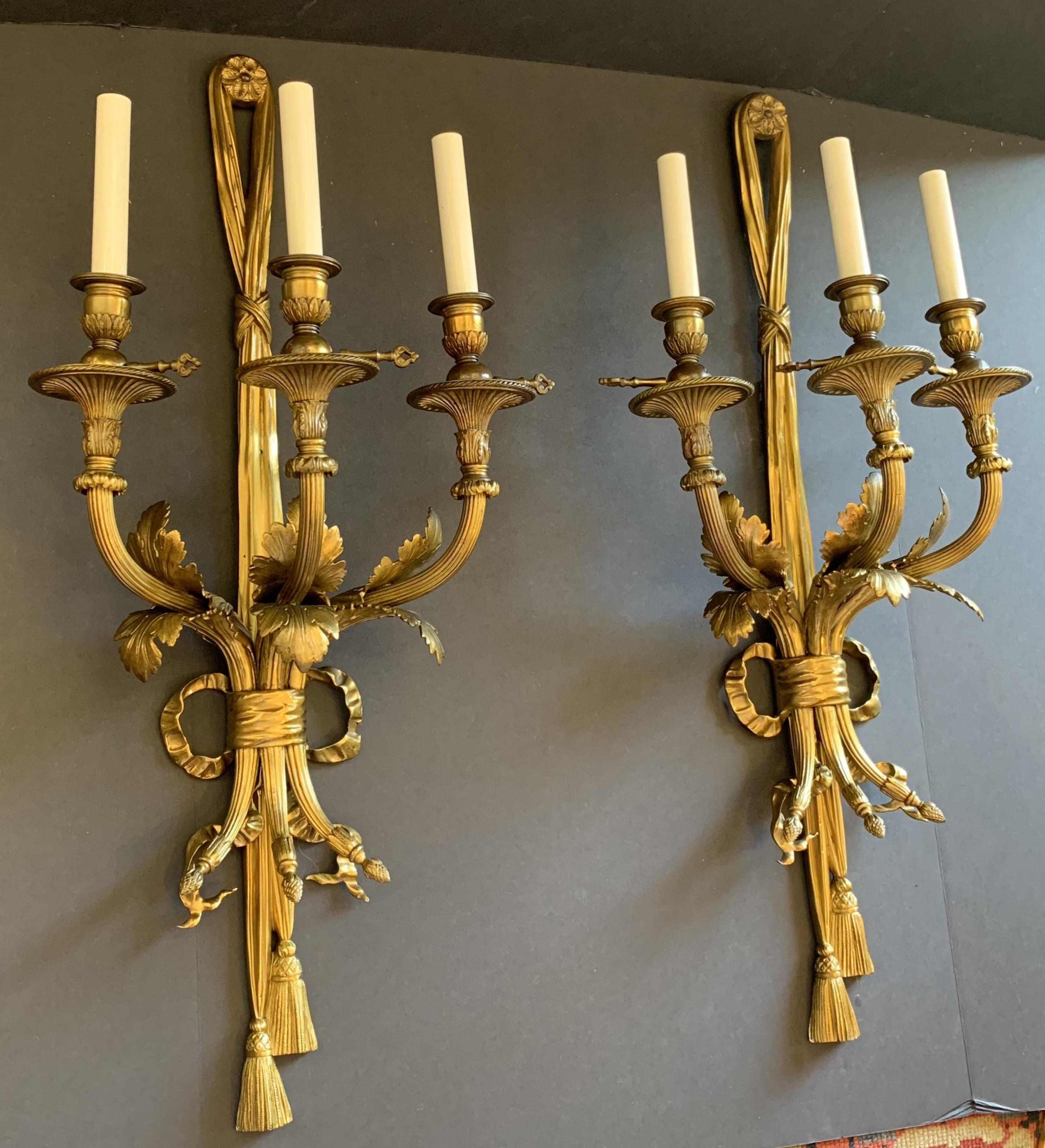 An outstanding large pair of doré bronze three-arm ribbon bow tassel sconces in the manner of E.F. Caldwell & Maison Millet.