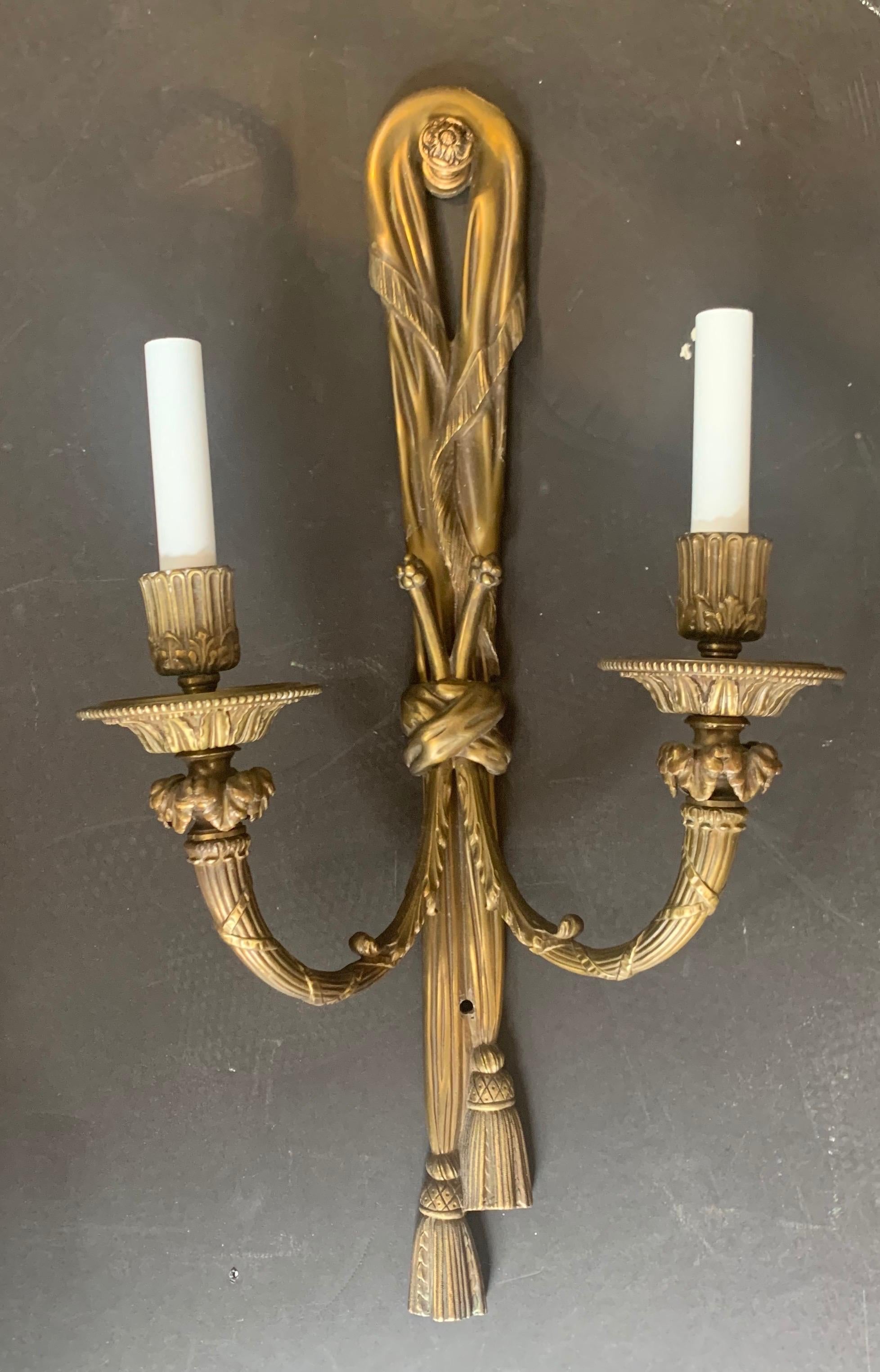 A wonderful large pair of gilt bronze E.F. Caldwell style two-light ribbon Tassel sconces.