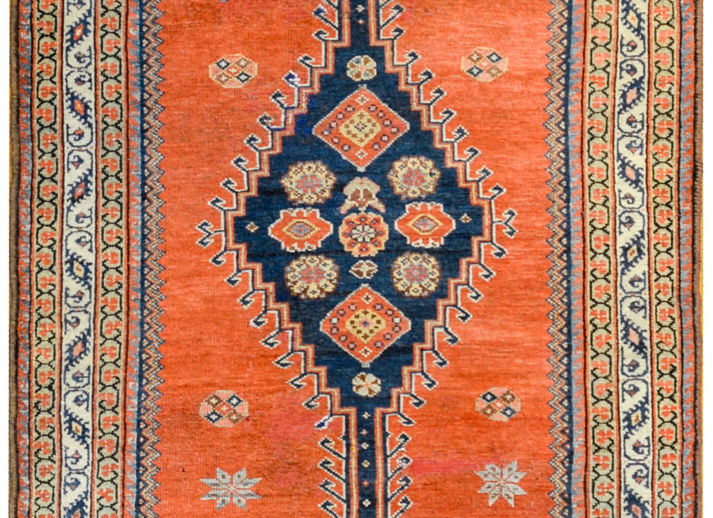A wonderful late 19th century Persian Azari runner with four large indigo medallions with stylized flowers on a crimson background. The border is thin with three petite floral and vine patterned stripes.
