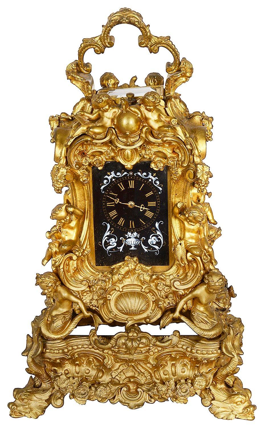 A late 19th Century French gilded ormolu ornate carriage clock. Having this wonderful scrolling foliate Rococo style case with numerous seated putti picking fruits, inset hand painted porcelain panels depicting cupids, supported by mermaids and