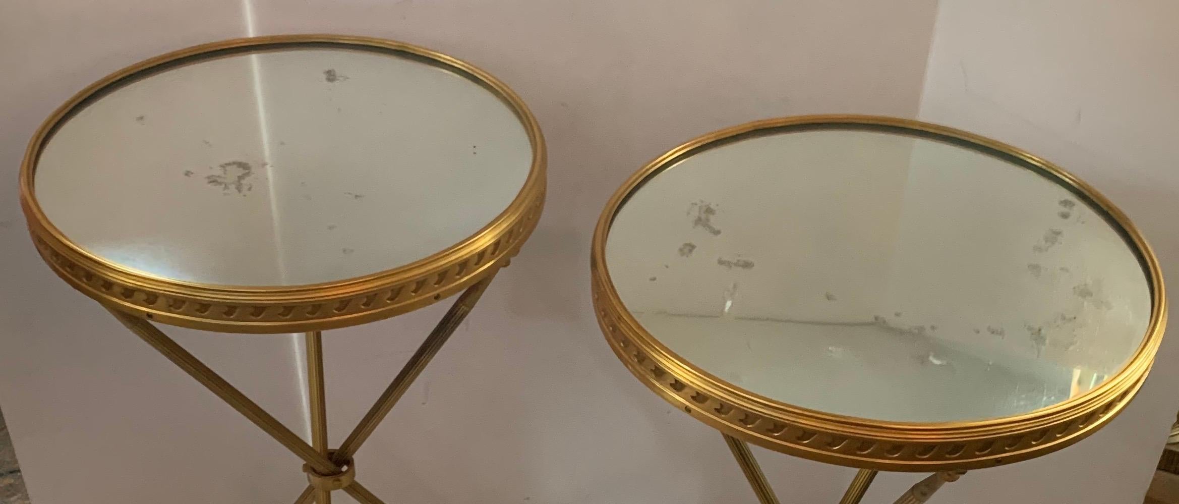 A wonderful Maison Baguès style gilt bronze and mirror top Hollywood Regency pair of round side tables.