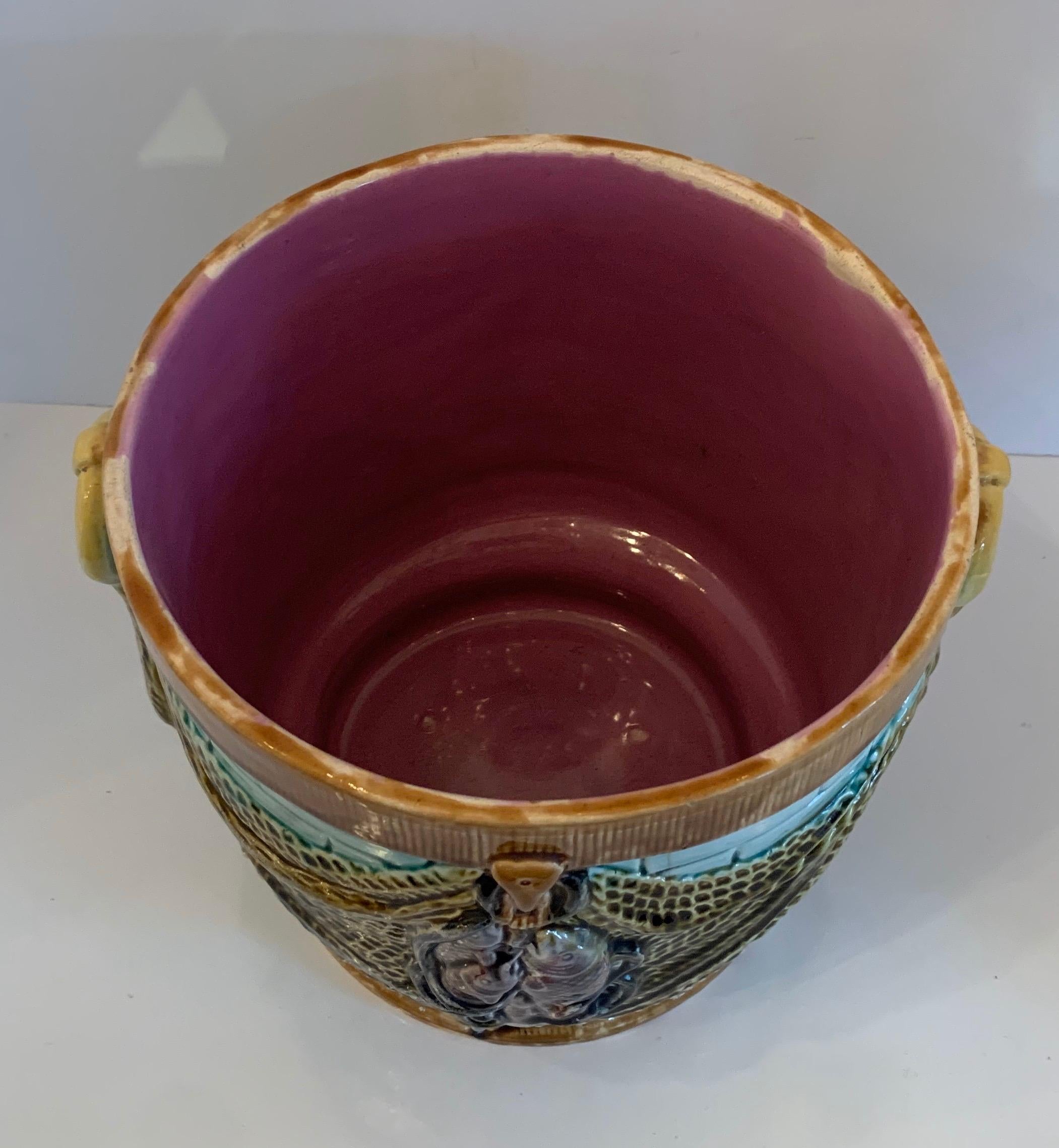 A wonderful Majolica jardinière centerpiece bowl cachepot planter with fish accents over draped fabric leading to ring handles on each side.
  