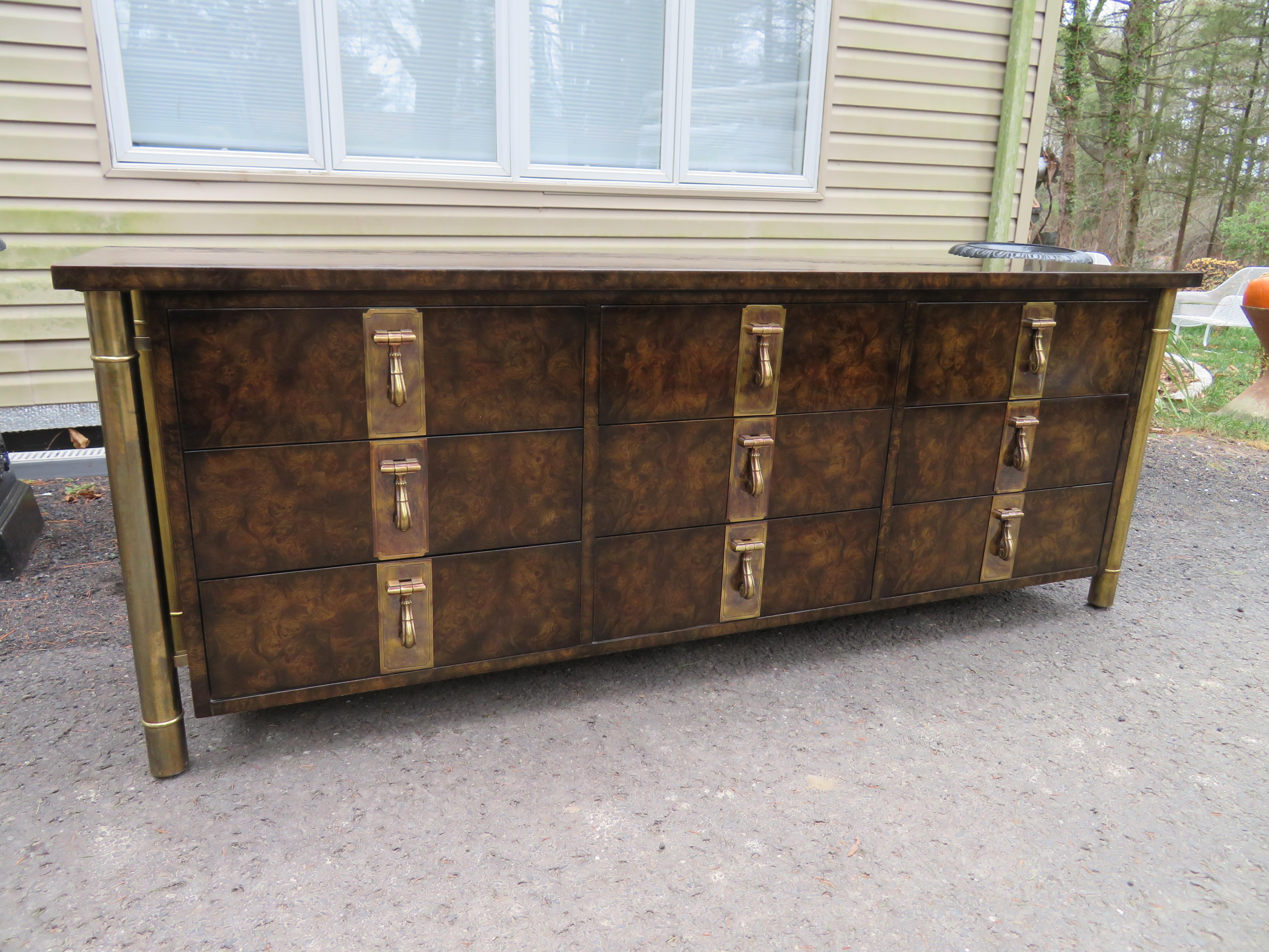 Wonderful Mastercraft burled walnut and brass credenza. This piece screams quality and old world craftsmanship with bold brass pulls and oversized cylindrical legs. We love the dark burled walnut wood contrasted with the patinated brass details and