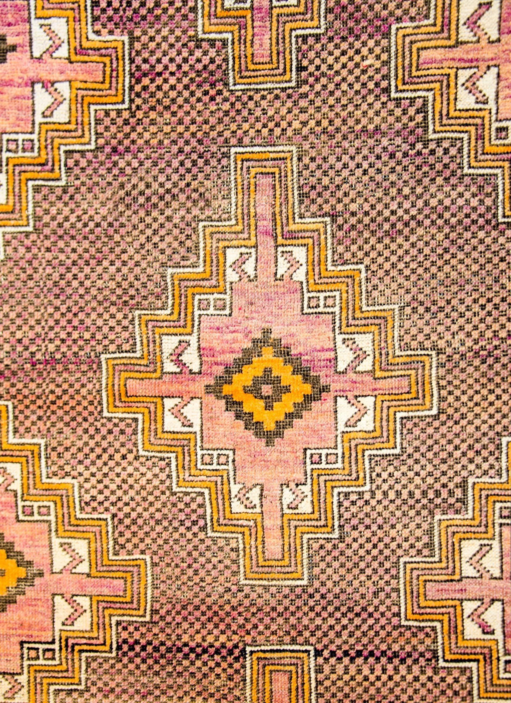 A wonderful mid-20th century Persian Baluch rug with three stepped diamond medallions woven in gold, pink, black, and white, on a beautiful small-scale black and violet checkerboard patterned ground. The border is simple, with a wide checkerboard