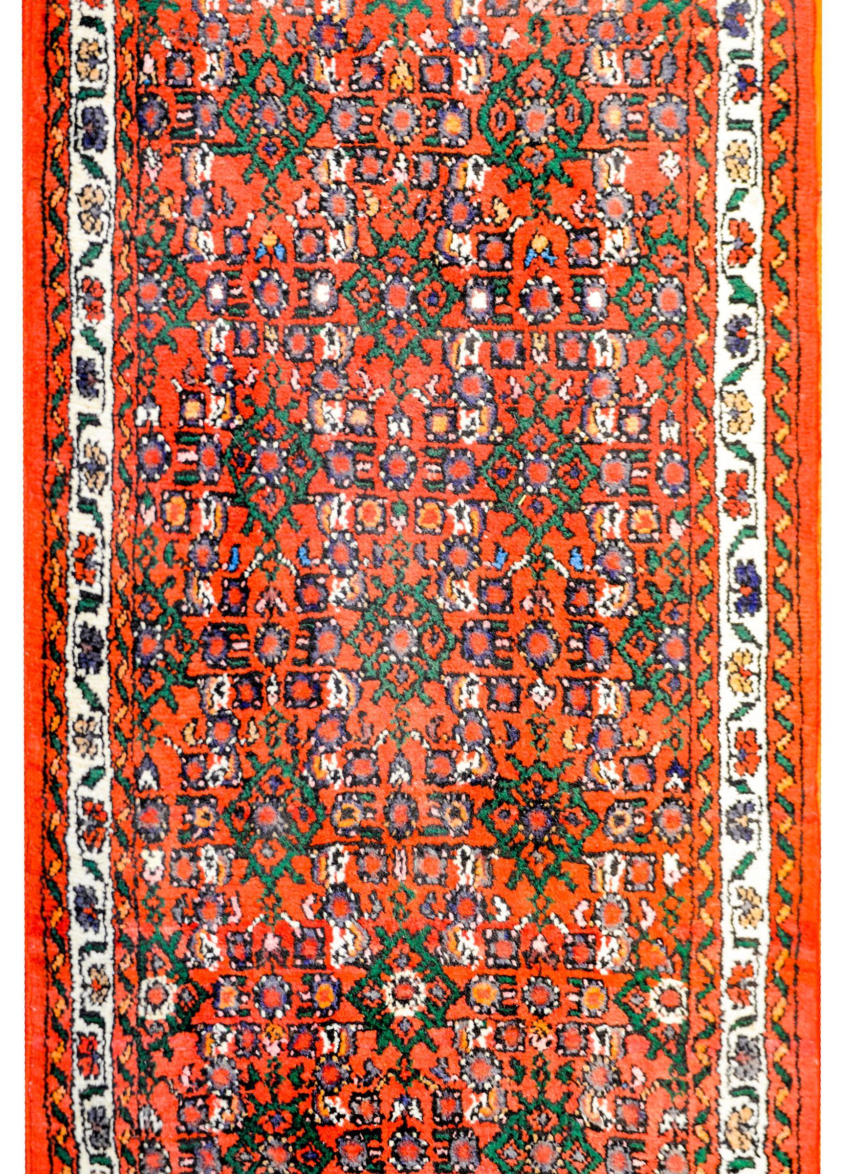 A wonderful mid-20th century Persian Dargazin runner with a fantastic all-over trellis and floral pattern woven in bold crimson, orange, green, and white vegetable dyed wool. The border is simple, with two thin petite floral patterned and scrolling