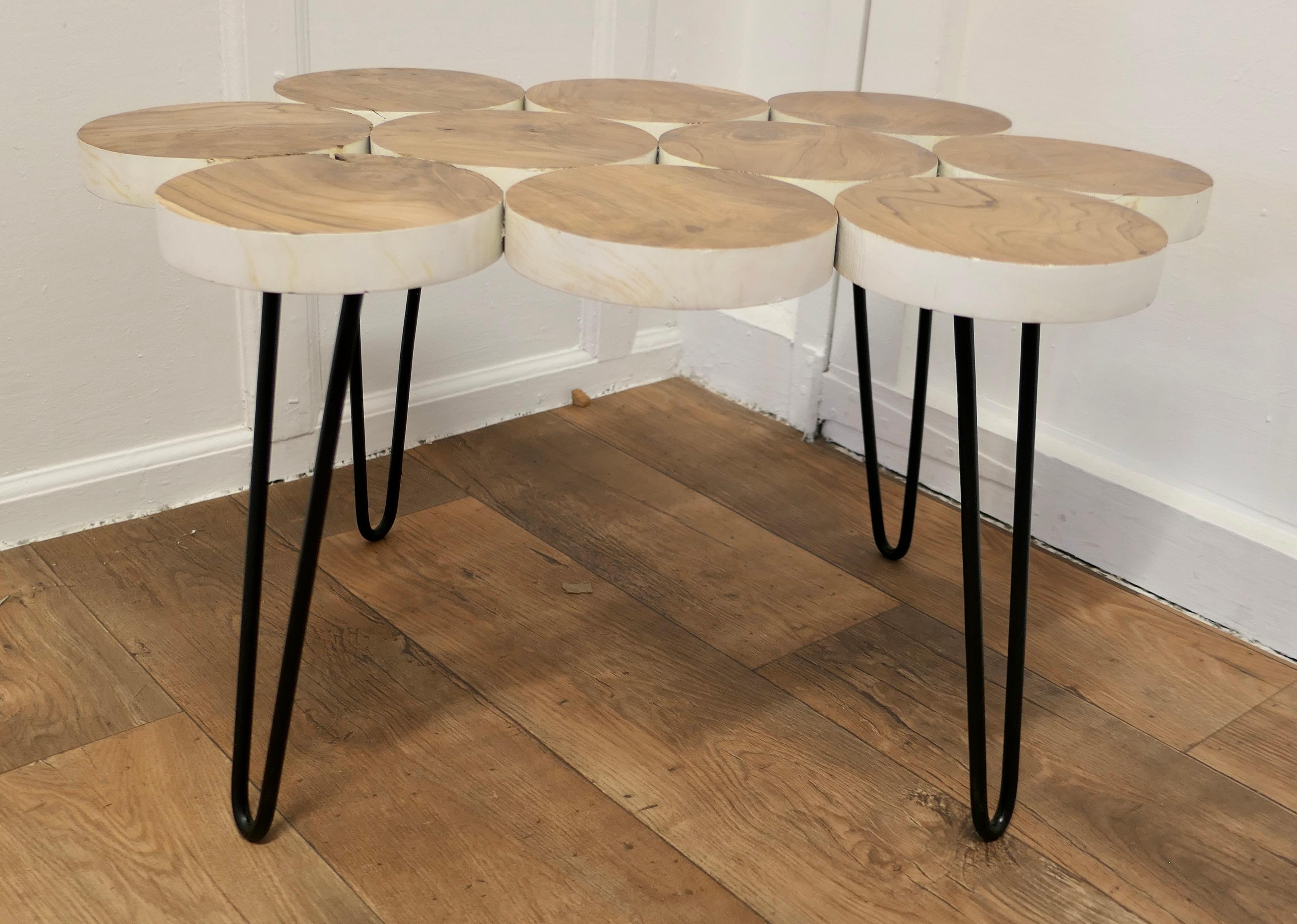 Wonderful midcentury Folk Art Olive Wood Table

The table top is made from slices of Olive wood which are screws together and set on black wire work legs
A charming look to the old wood and making a statement piece Coffee or Cocktail table
The