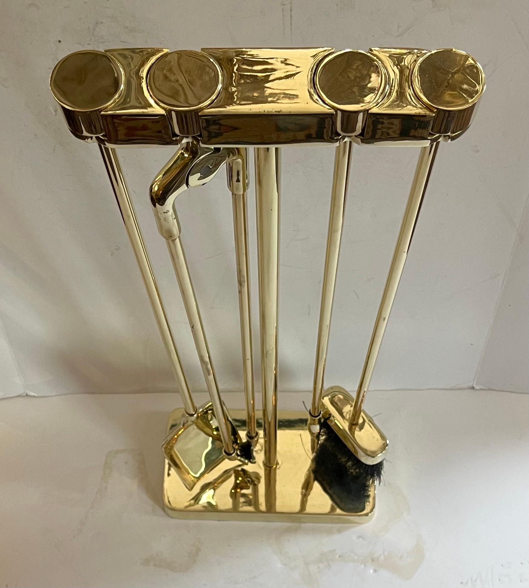 Wonderful Mid-Century Modern four piece polished brass fire place tool set consists of a stoker, shovel, brush and log holder, neatly suspended from a polished brass 