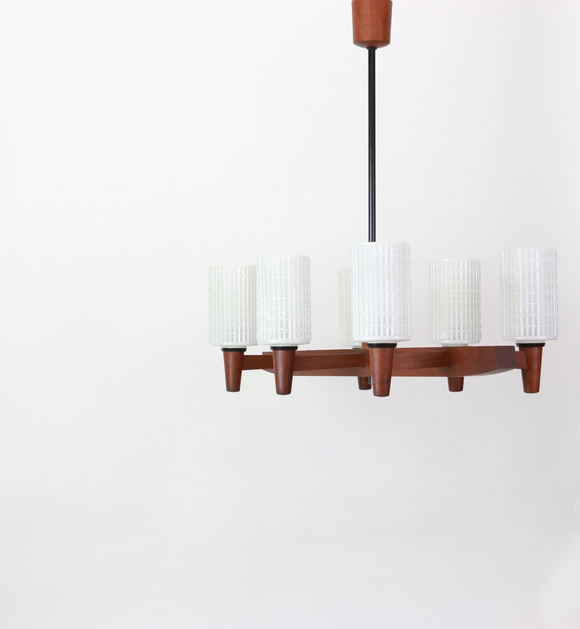 A wonderful midcentury teak chandelier. A unique, timeless and elegant masterpiece of Danish Furniture design. The light sculpture impresses with clear lines and perfect craftsmanship of the materials wood and opal glass. 

High quality and in