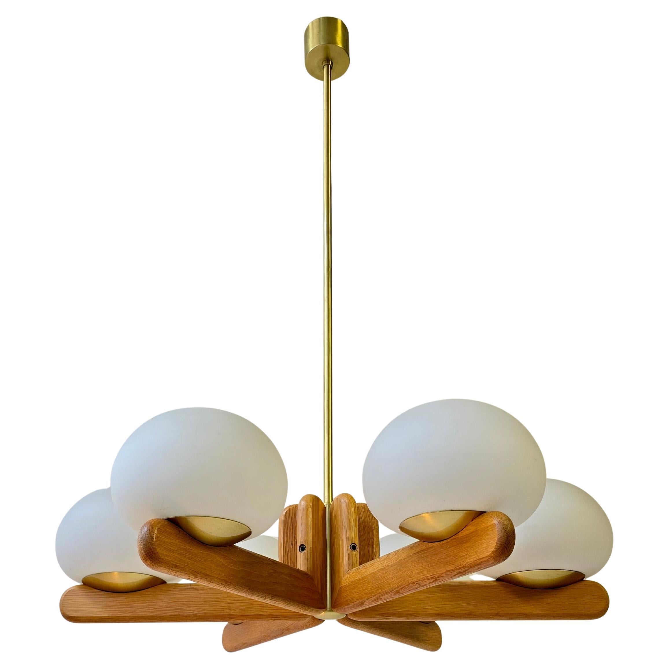 Questo splendido lampadario in quercia della metà del secolo scorso è un capolavoro elegante e senza tempo realizzato da Kaiser Leuchten in Germania negli anni Sessanta. Il design incarna l'essenza del minimalismo scandinavo e della precisione