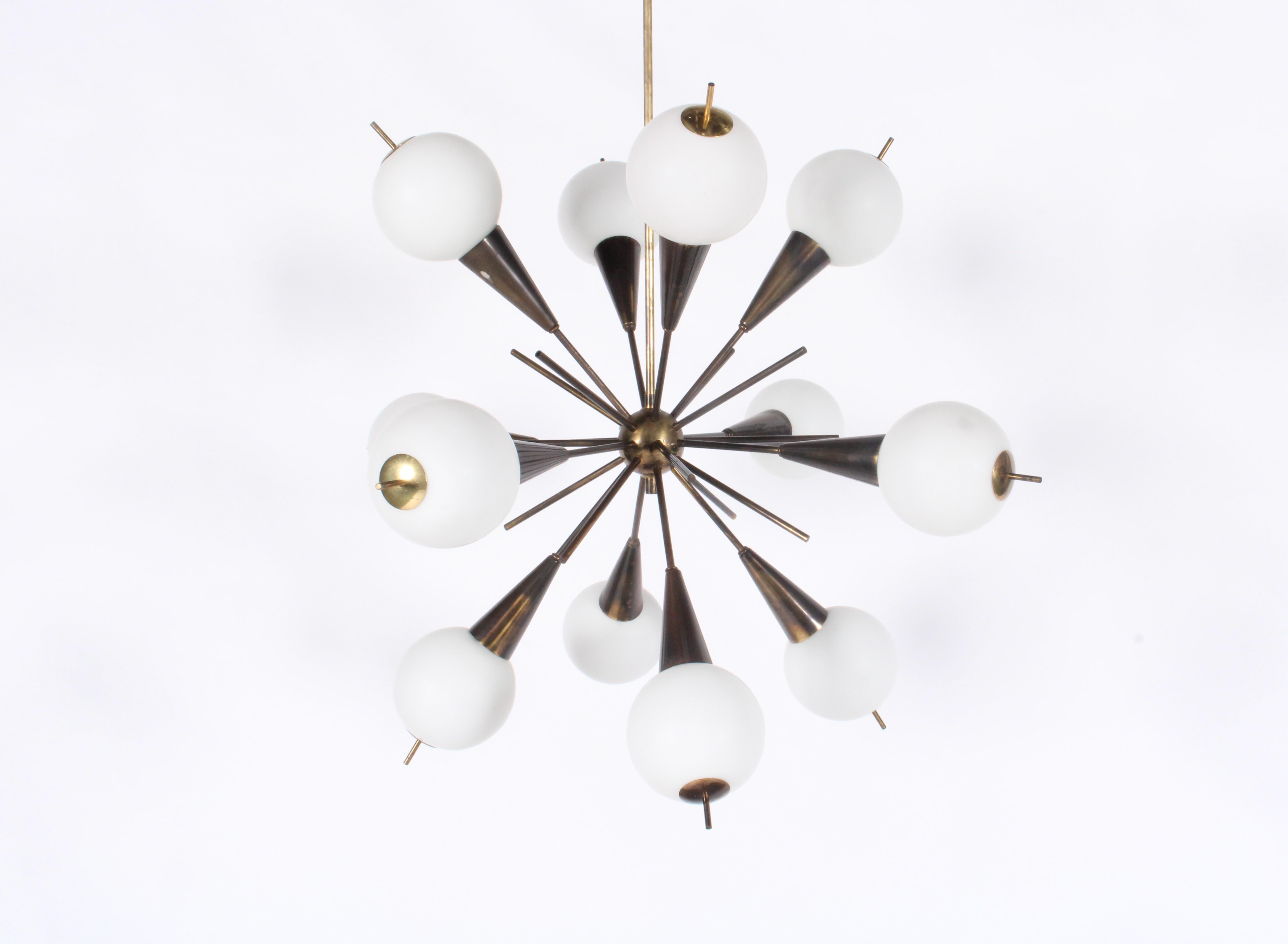 Acquired è lieta di presentare in vendita questo incredibile lampadario originale Sputnik Modern italiano del 1955 circa. Un modello a dodici rami con paralumi in vetro opalino, questo pezzo ha una patina incredibile sulla struttura in ottone. I