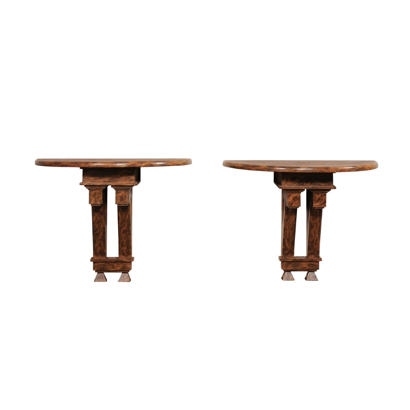 An English pair of wall-mounted demi consoles from 19th century fragments with faux burl wood finish. These one of a kind antique console tables from England each have a demi-shaped (half-moon) top, which upon an is raised upon an architectural