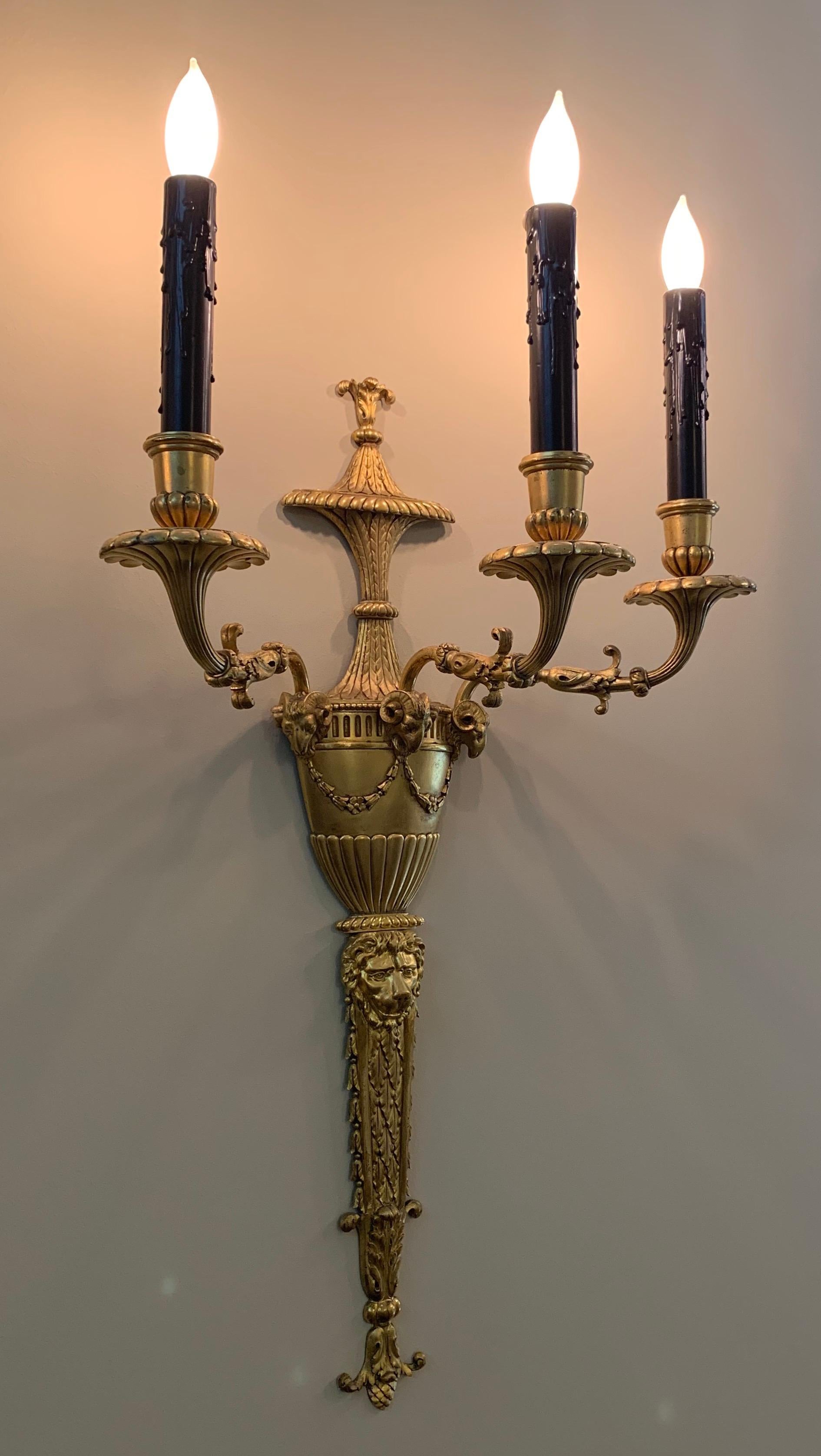 A wonderful pair of Caldwell style French doré bronze neoclassical / Empire 3 candelabra light lion, urn and ram's head form sconces.