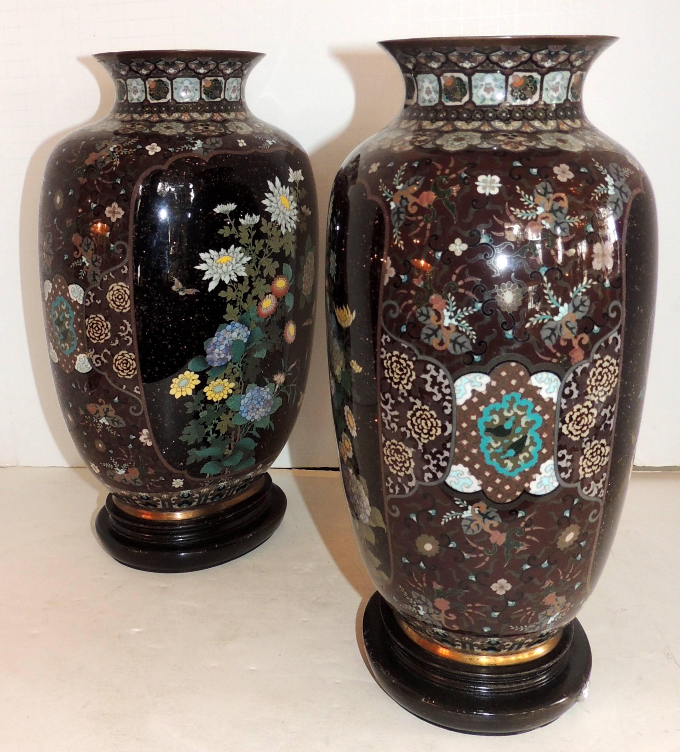 A wonderful pair of Japanese Meiji cloisonne enameled vases with flower bouquets and spray and is in an urn form previously drilled on the bottoms for lamps on wood bases.