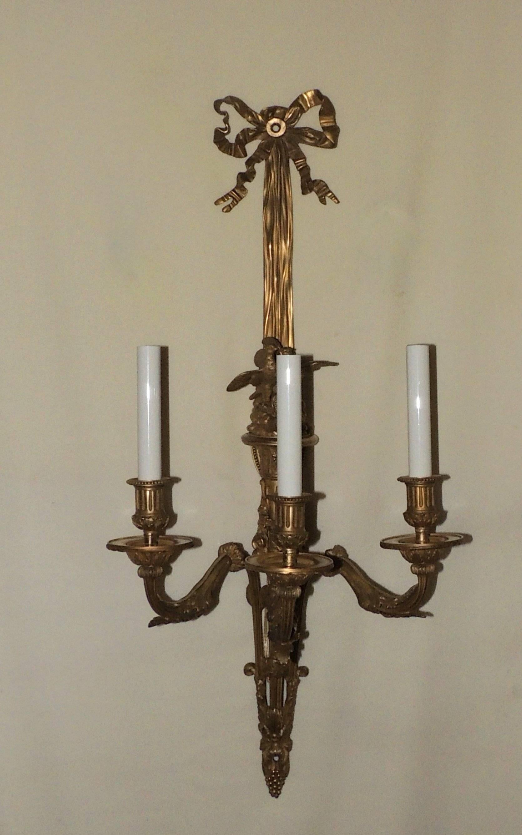 A wonderful pair of dore bronze three-arm sconces with beautiful ribbon bow top,
three arms and a pair of love birds sitting in the centre. Beautiful filigree detail embellishes the three arms and the bottom of these sconces.

Measures: 28