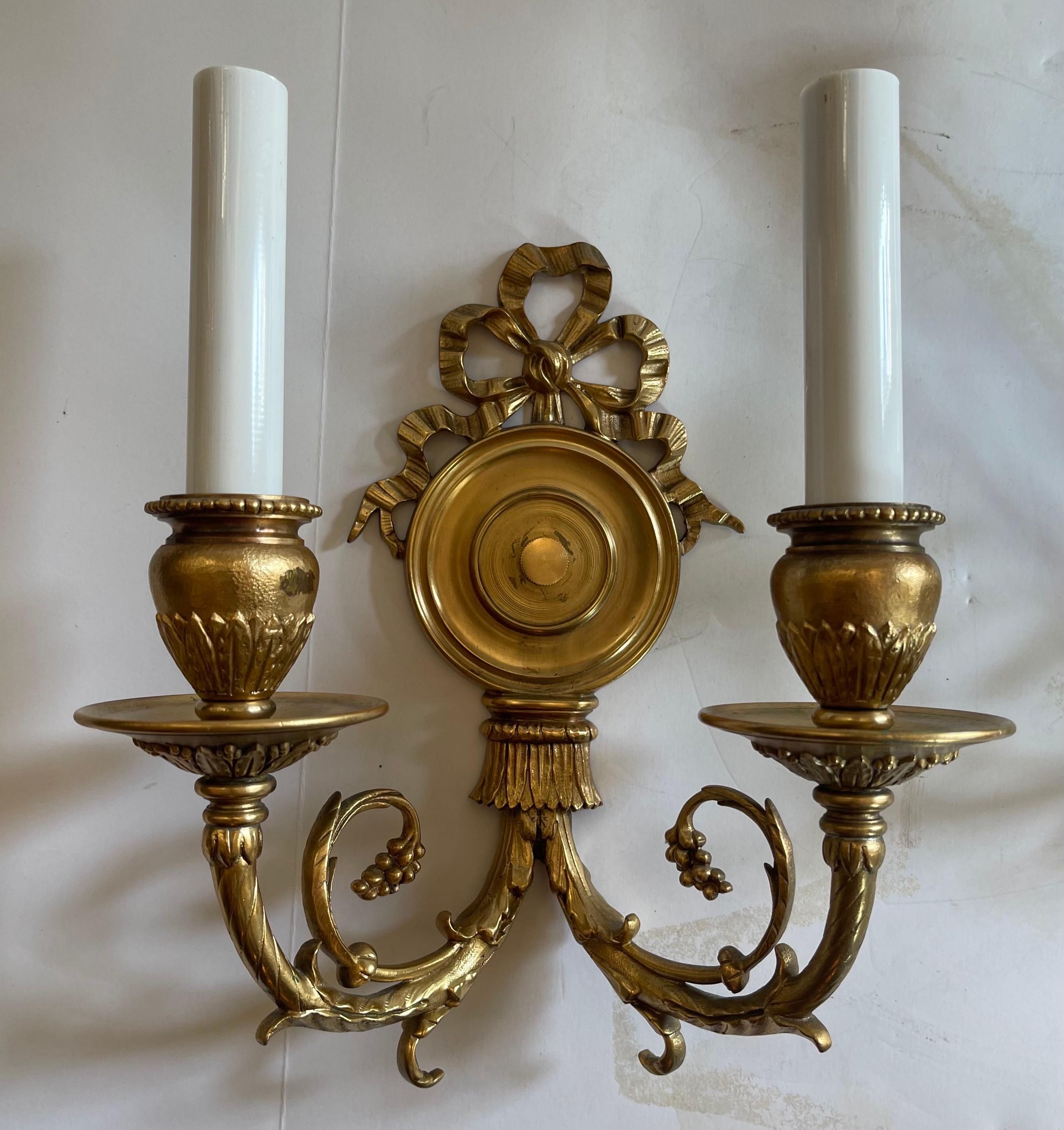 A wonderful pair of French dore bronze bow top wall sconces in the manner of E.F. Caldwell.