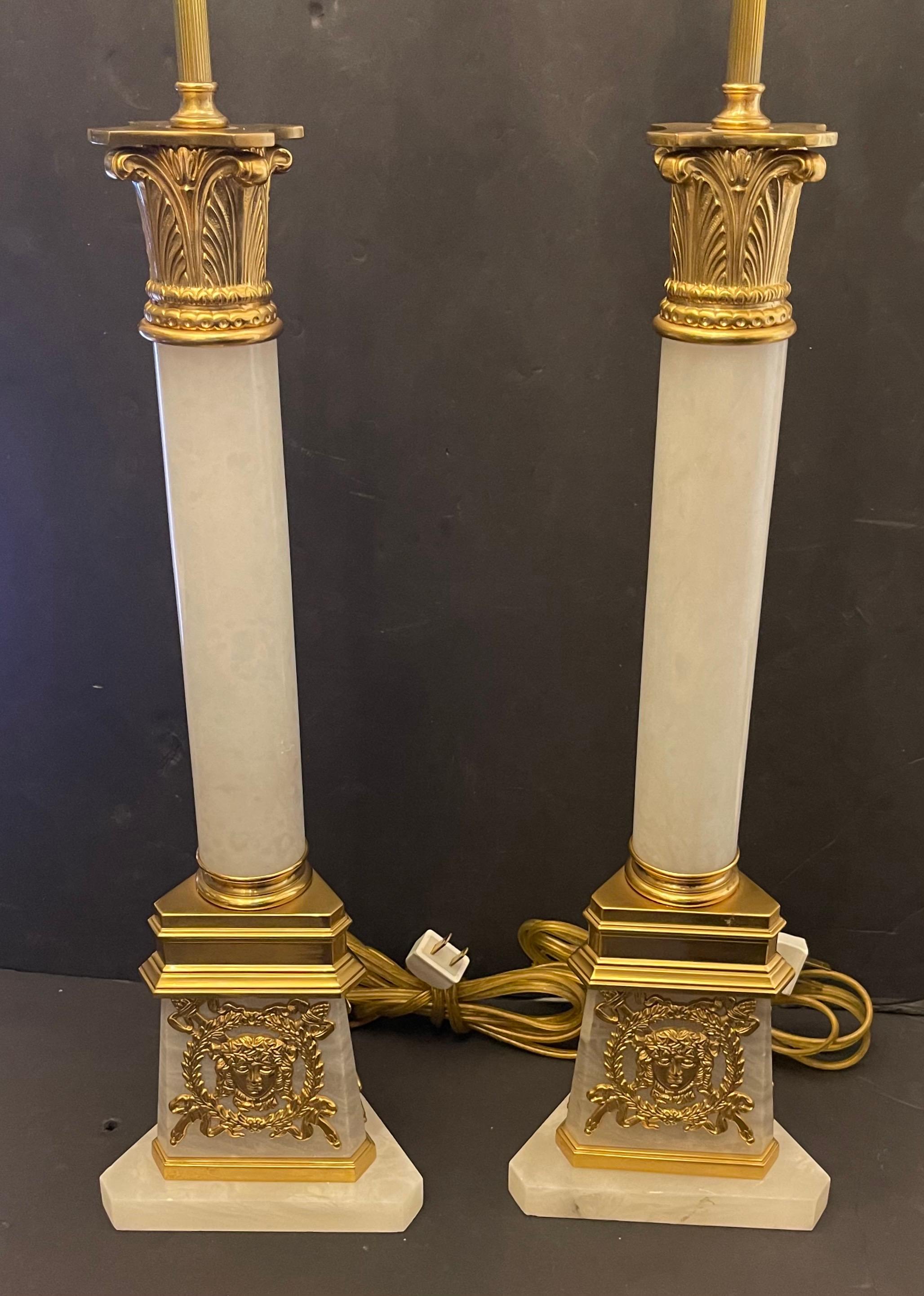 Meravigliosa coppia di lampade neoclassiche Regency in bronzo dorato e marmo a forma di colonna corinzia, ciascuna con placca Medusa montata su una base triangolare.