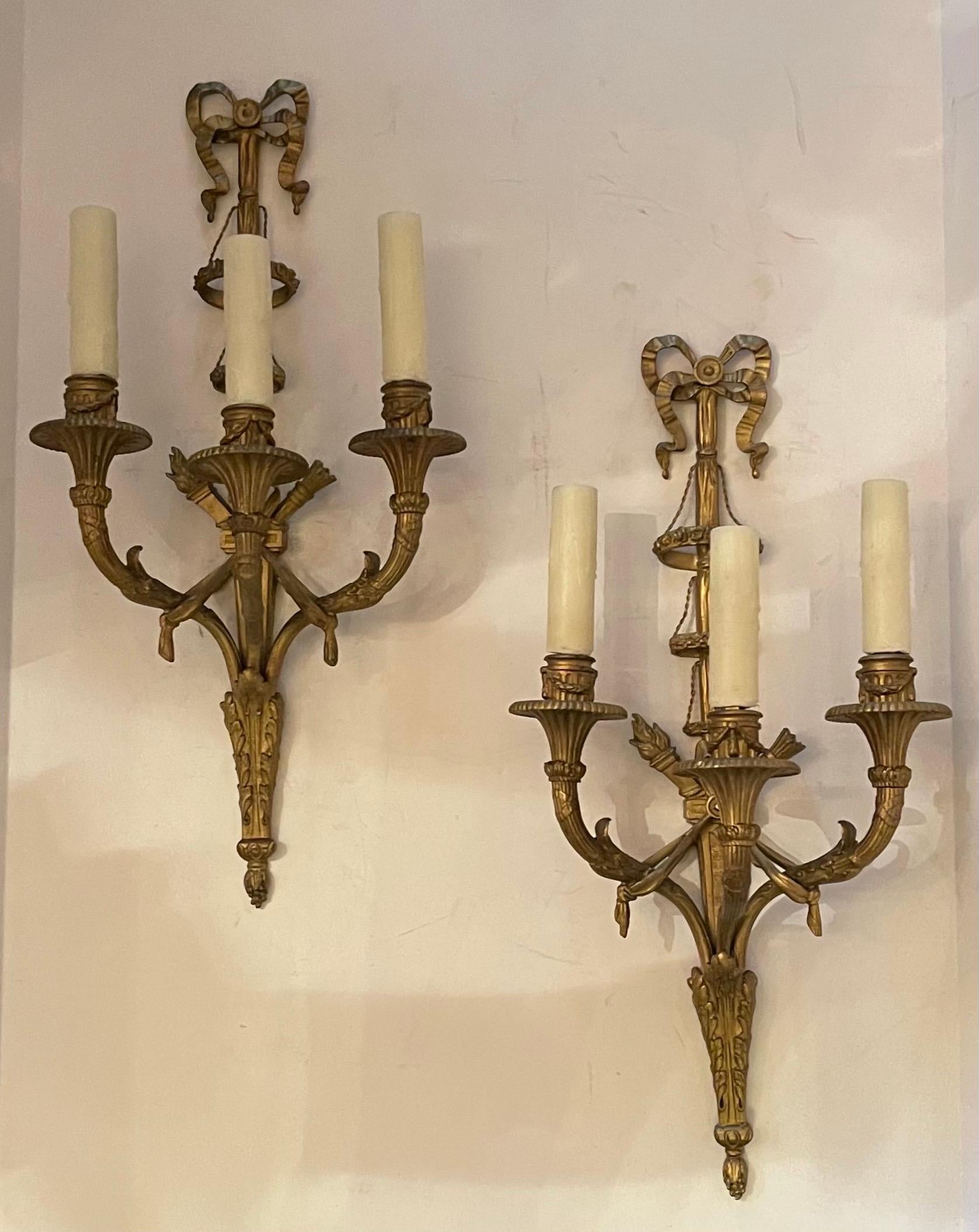 Magnifique paire d'appliques murales à trois candélabres en bronze doré à tête en forme d'arc, avec des guirlandes et des paniers sur la tige centrale, à la manière d'E. F. Caldwell.
