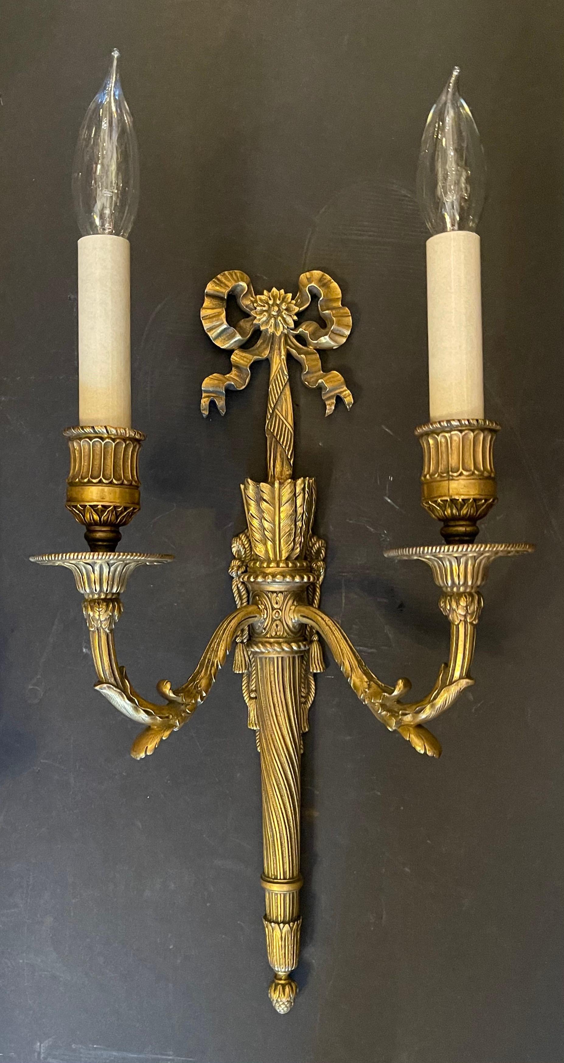 A wonderful pair of French gilt doré bronze bow torchiere two-light sconces in the manner of Caldwell.