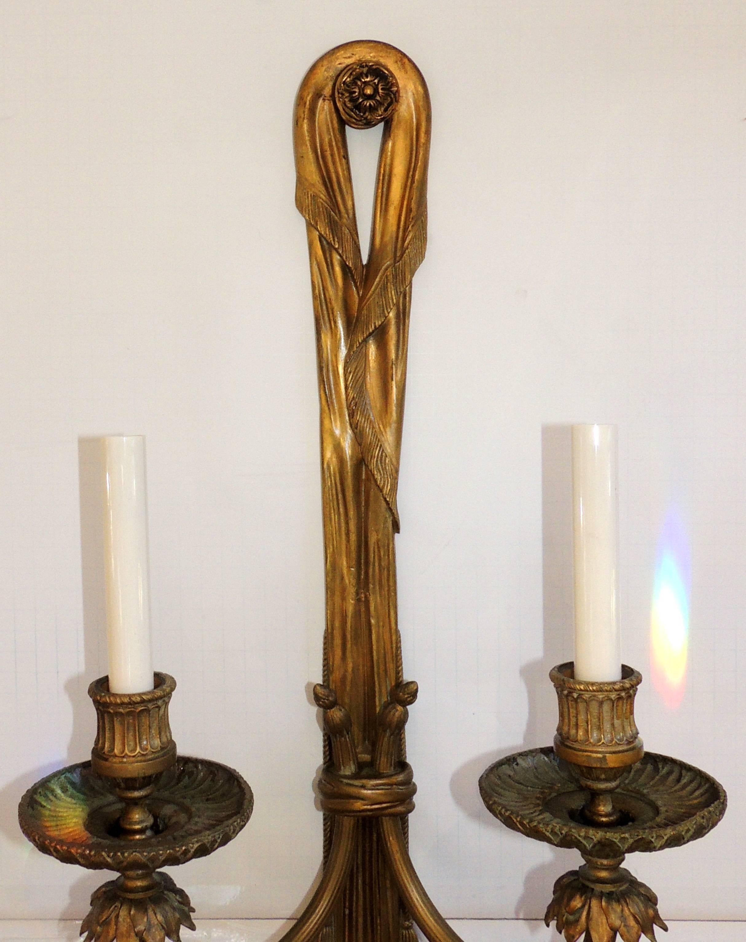 An outstanding pair of large gilt bronze stamped E.F. Caldwell two-arm / light ribbon tassel wall sconces, completely rewired with new wires and sockets.
  