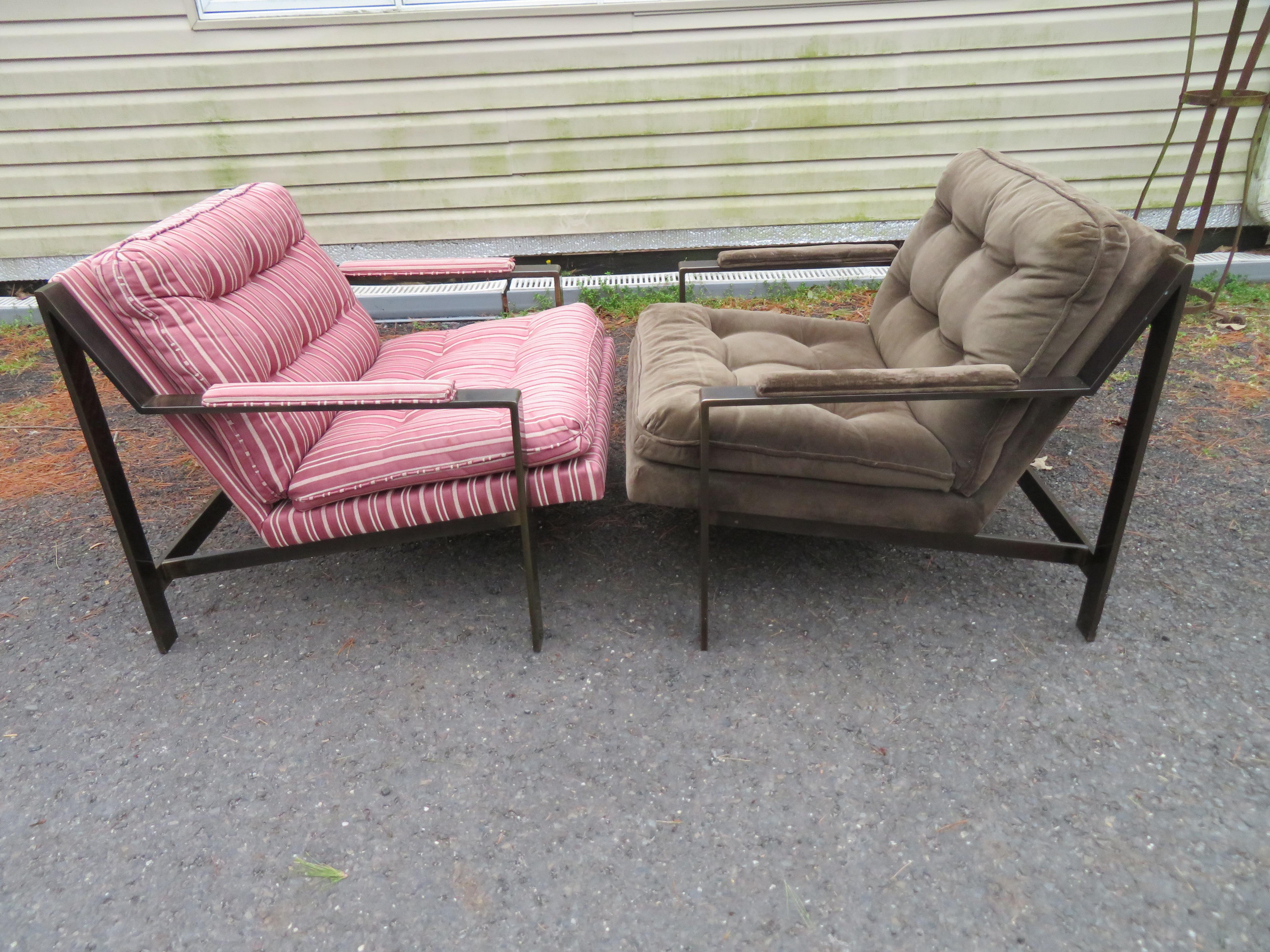 Handsome pair of Milo Baughman style brass lounge chairs. We love the time-worn patina these have obtained giving them a real sense of vintage charm. The mismatched upholstery is in usable condition but is dated so we do recommend reupholstery for