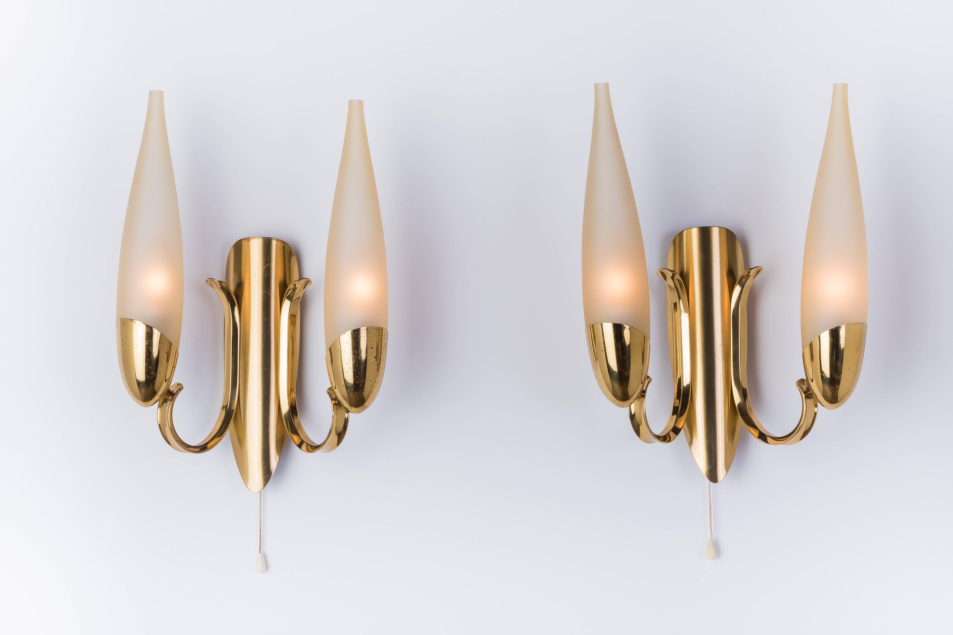 This wonderful pair of 1950s Italian sconces in the manner of Stilnovo features a candelabra inspired design with a brass frame and two filigree hand-blown conical form lampshades.

Made in Italy, Circa 1950.