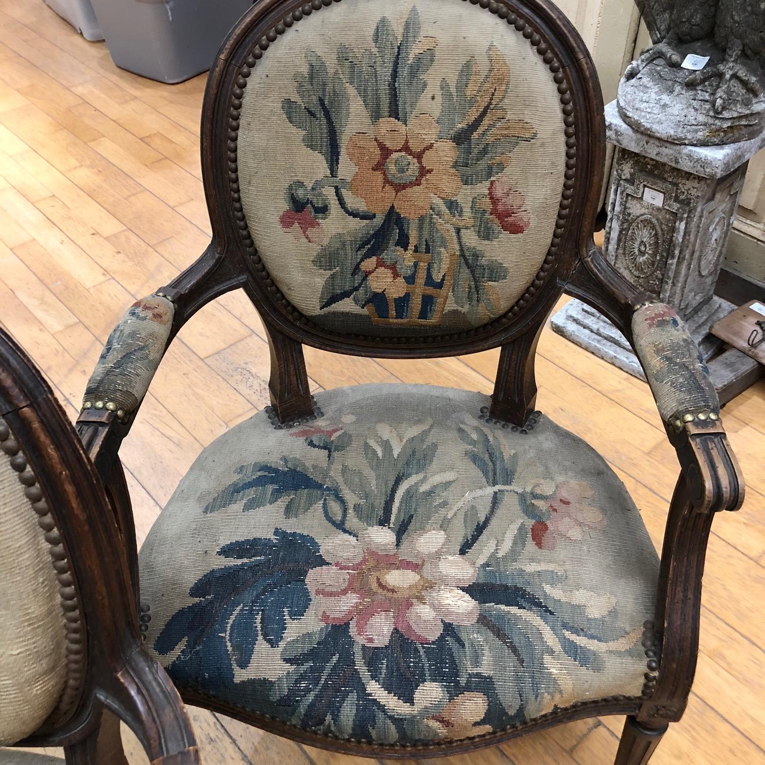 Two charming French armchairs having carved wood frames and gorgeous original floral tapestry upholstery with coordinating plaid fabric on the backs. Arm height 24. #4435