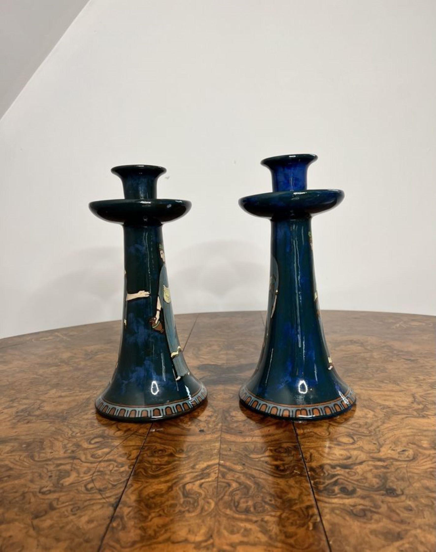 Wonderful pair of antique Decoro England candlesticks having a wonderful pair of shaped candlesticks with a blue ground, hand painted with figural scenes in blue, green, yellow and brown colours raised on circular patterned bases. 
Stamp to base as
