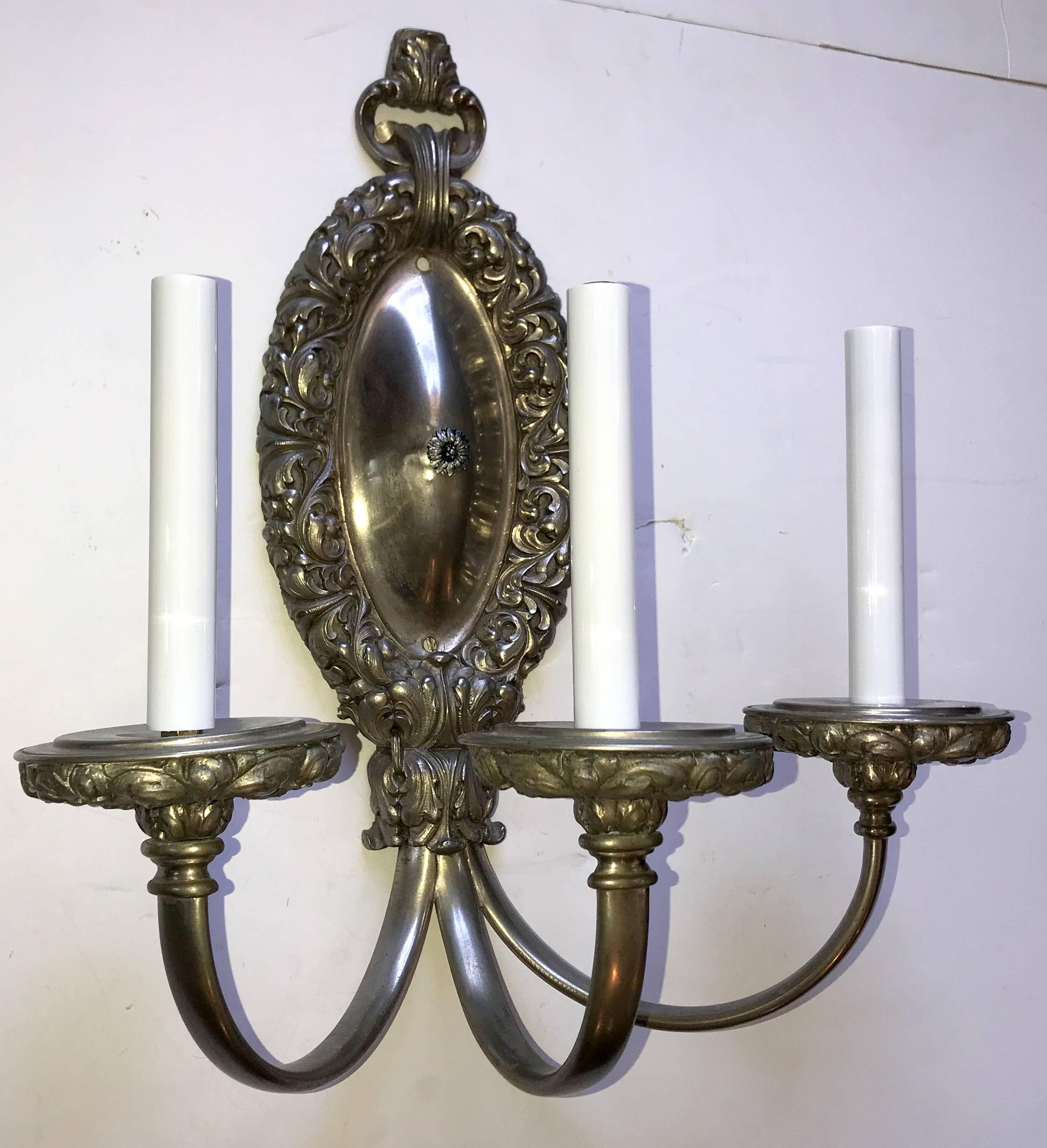 A wonderful pair of large Caldwell brushed silvered bronze neoclassical oval filigree three-light sconces completely rewired with new candelabra sockets.