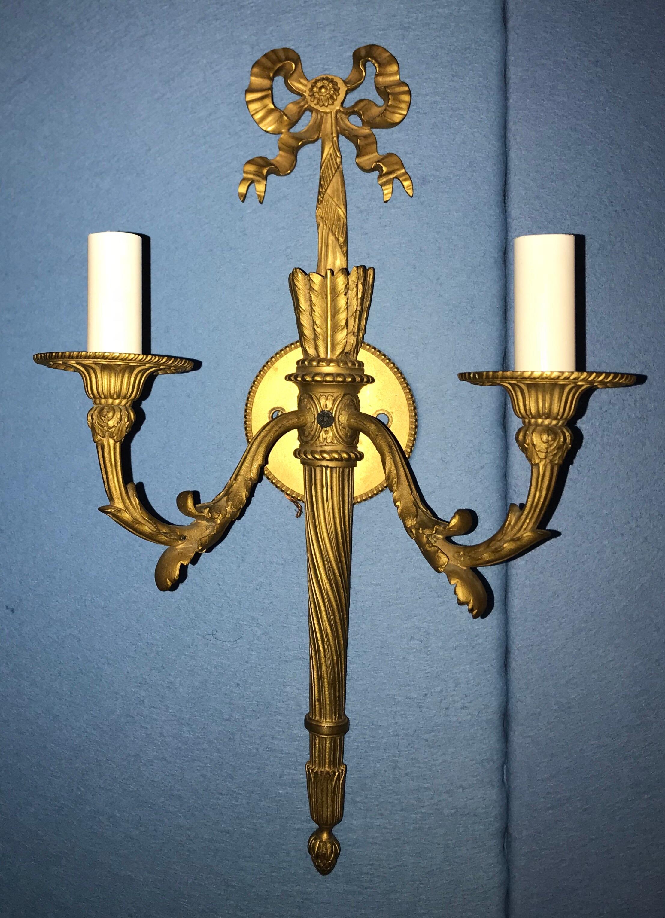 A wonderful pair of French doré bronze bow top and flame two candelabra light filigree sconces.