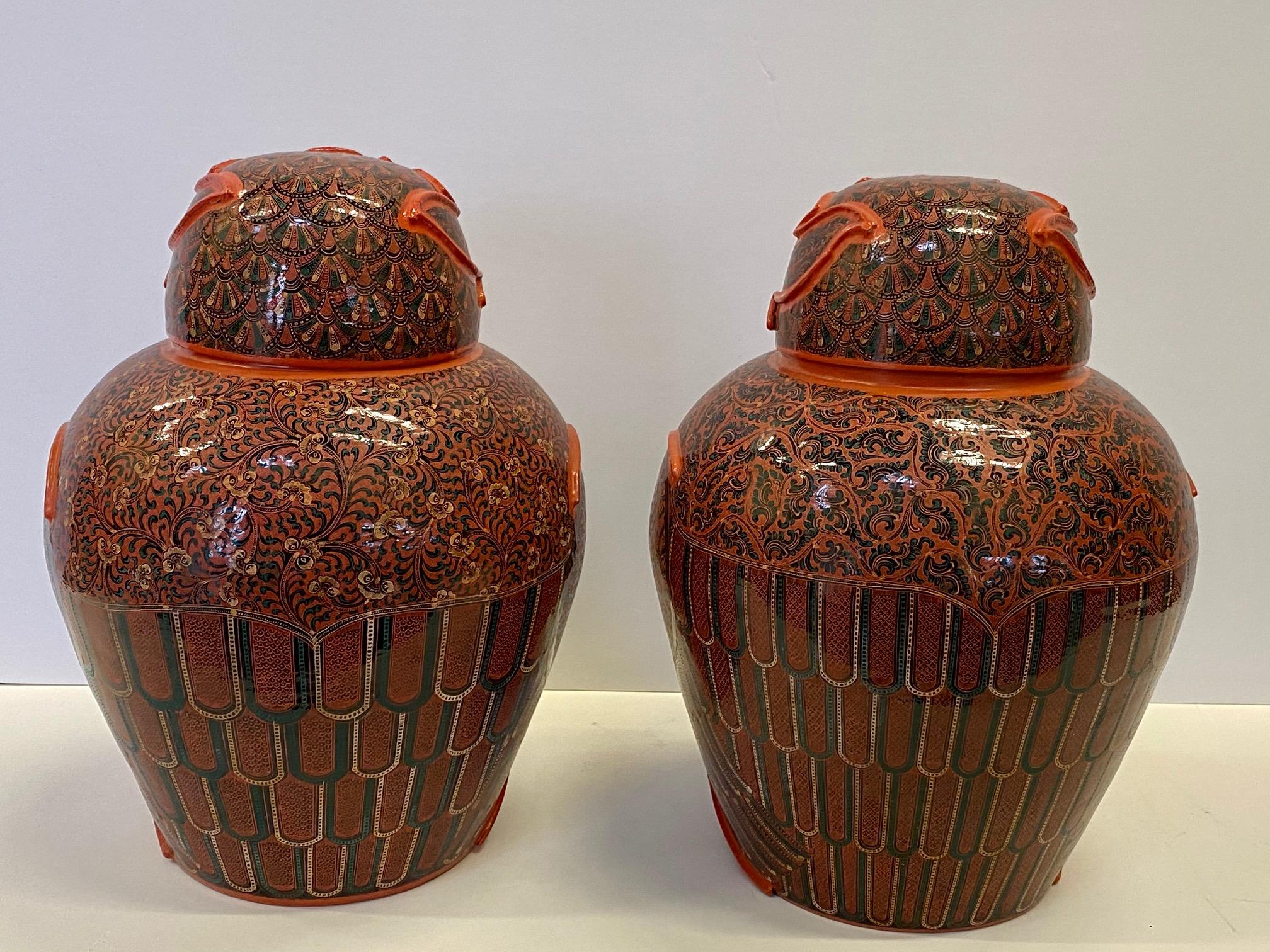 A marvelous pair of intricately hand painted Burmese owl jars with lids having an eye-catching color palette of red, green and orange lacquered papier mâché.