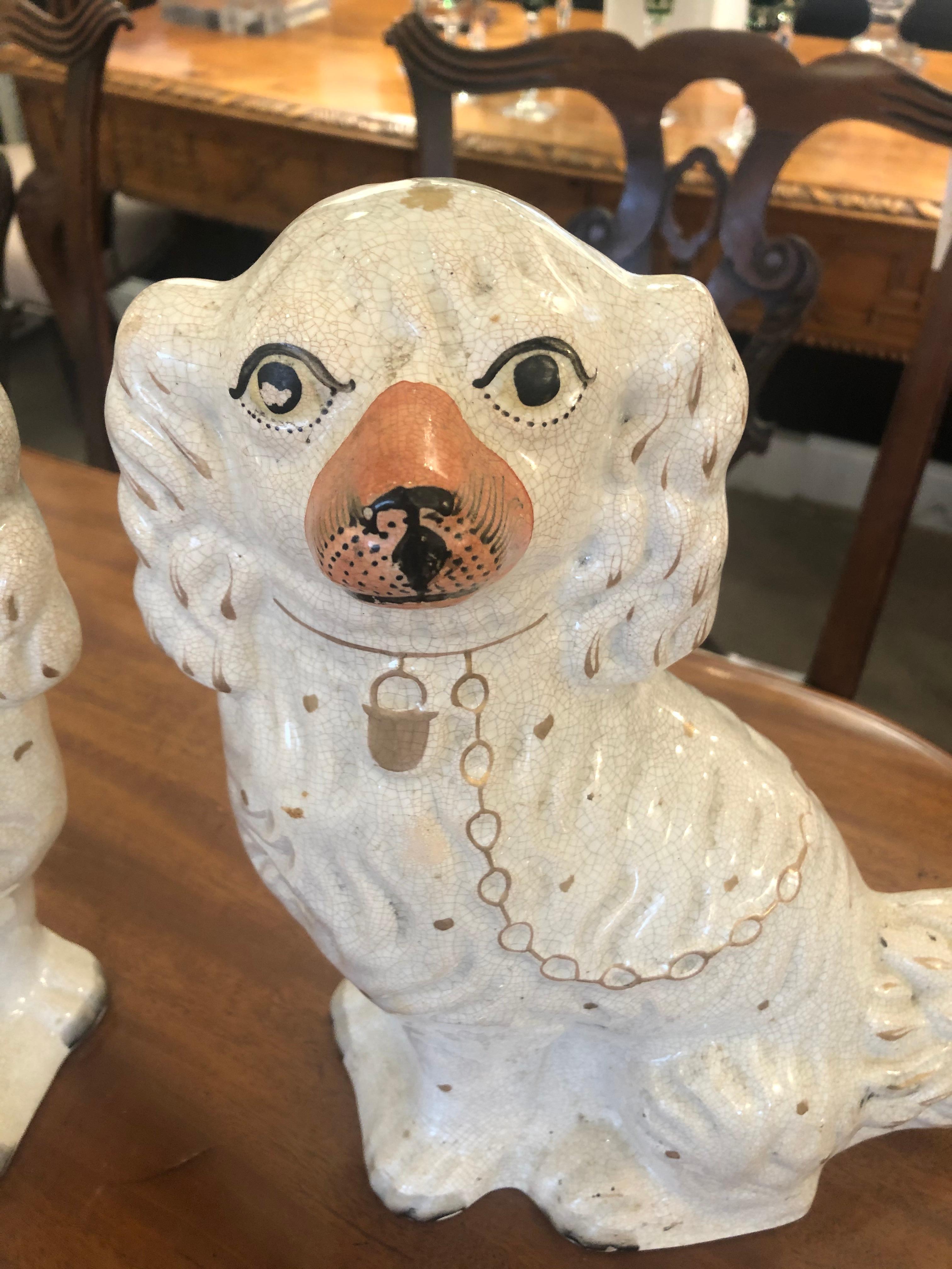 Classic stately pair of Staffordshire porcelain spaniel dogs having black eyes and details with off white color and terracotta snout and embellishments.