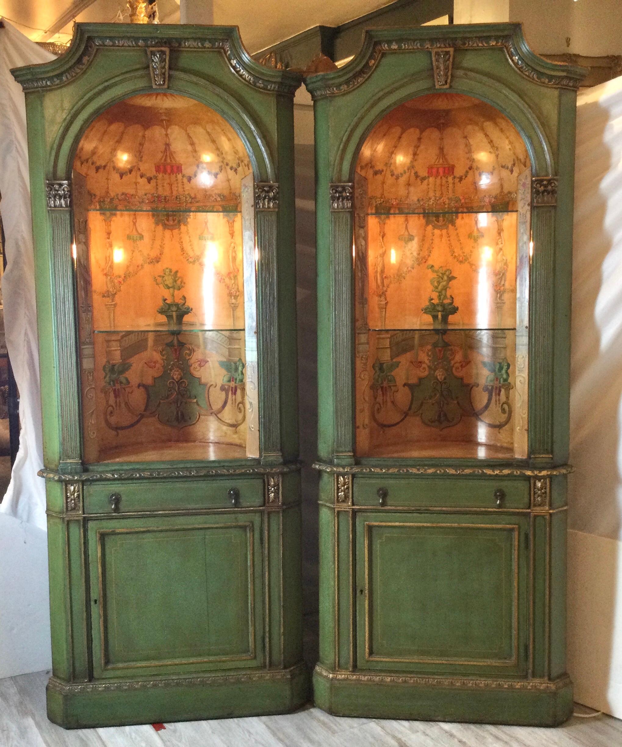 Wonderful pair of neo classical corner cabinets w/ hand painted curved interiors. The interiors have been professionally cleaned. Cabinets are green with gold trim. Domed interiors have removable glass shelfs. The cabinets are 2 parts. Each