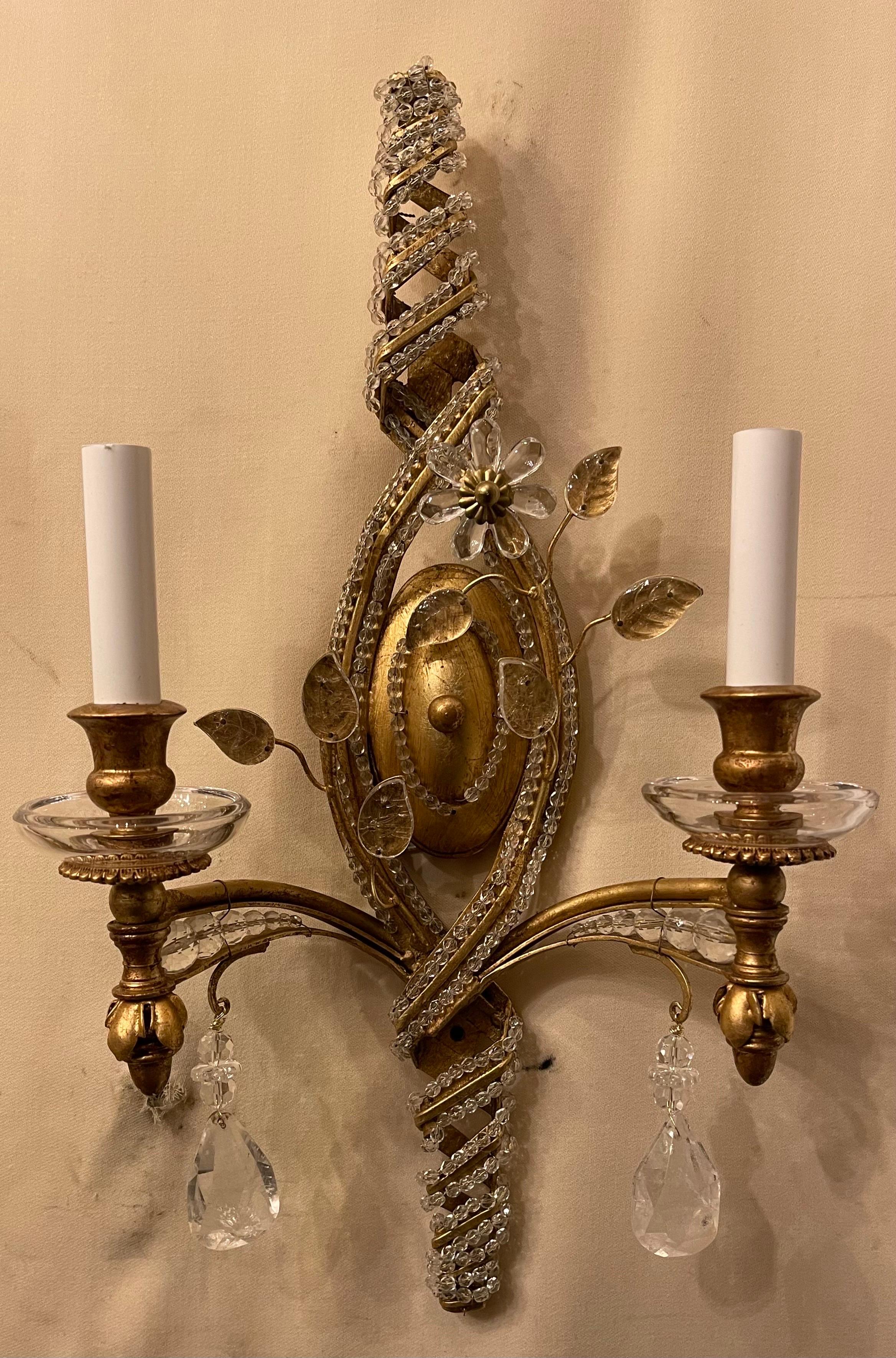A wonderful pair of gold gilt, rock crystal drop Maison Bagues style sconces with beaded spiral design leading to two candelabra lights situated inside clear cups. The sconces have been rewired with new sockets and come ready to install with