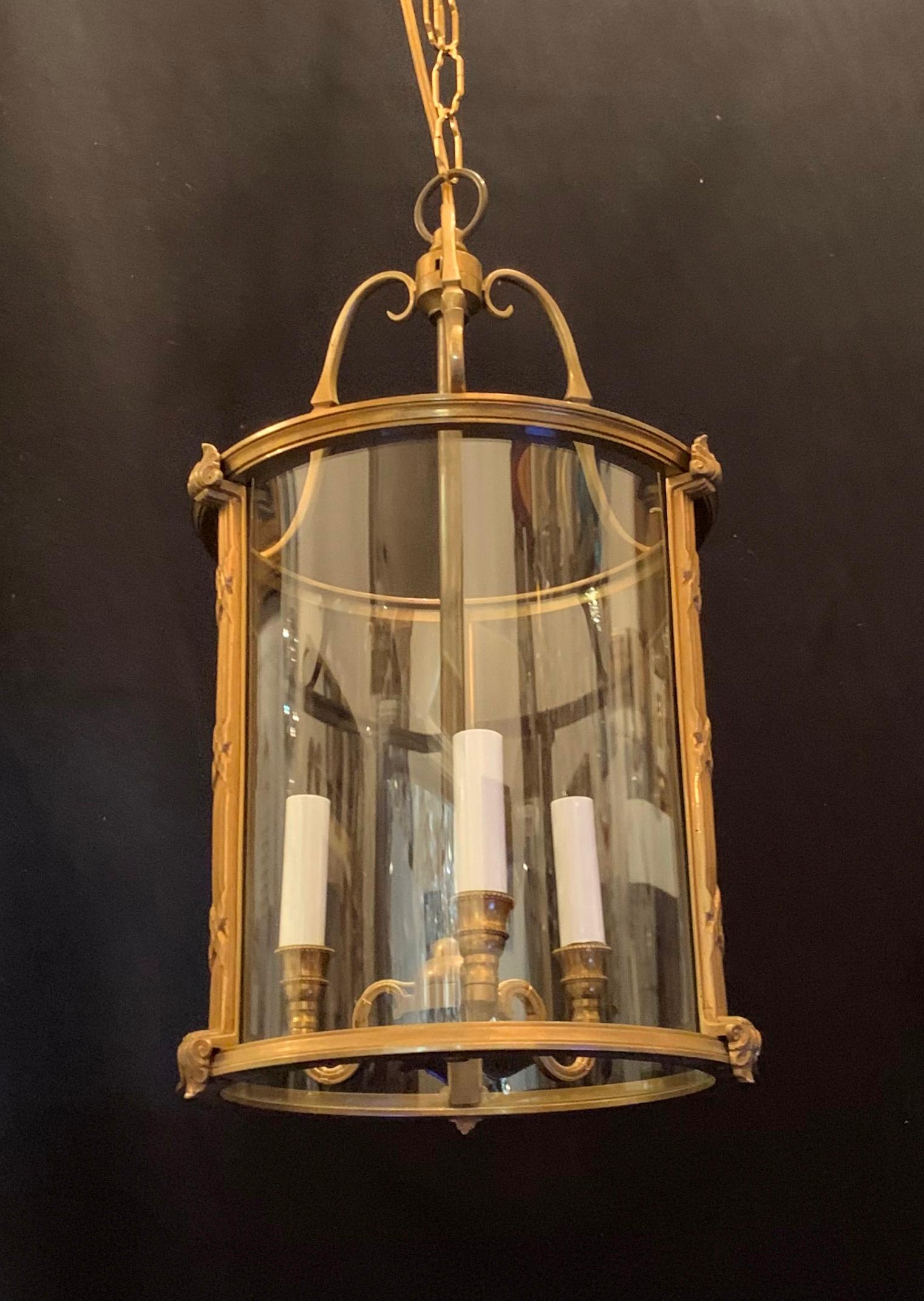 Perfect for a hallway or over a table or island. Classic gilt doré´ bronze and curved glass three candelabra light lantern. With beautiful scrolls curving at the top and supporting the lights, and beautiful etching around the bronze edges and