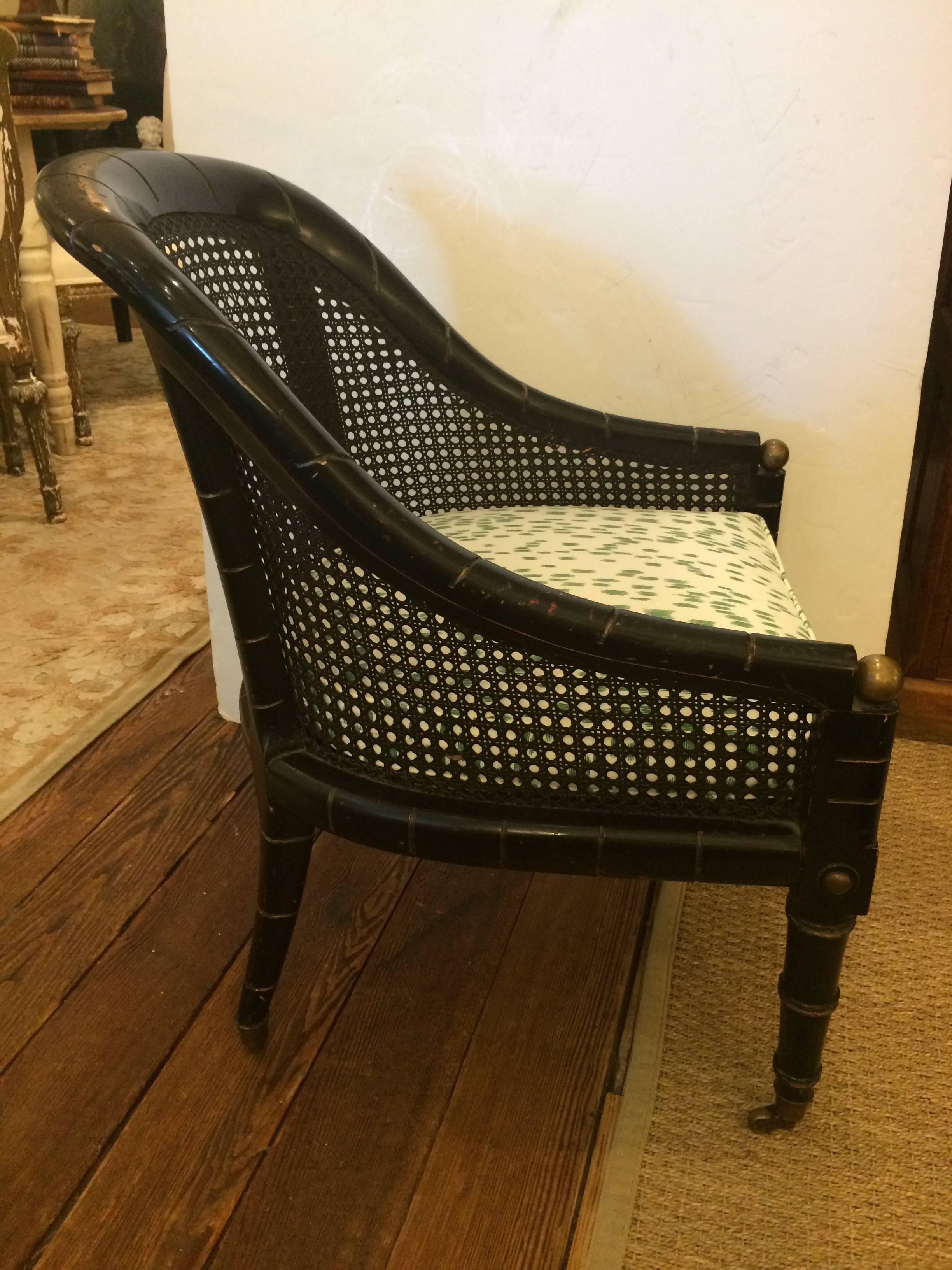 Chic black ebonized wood compact occasional chair having faux bamboo style legs with brass ball finials and decoration as well as caned back and seat. There's a new stylish cushion in Brunschwig and Fils green and white fabric. Seat depth 19.