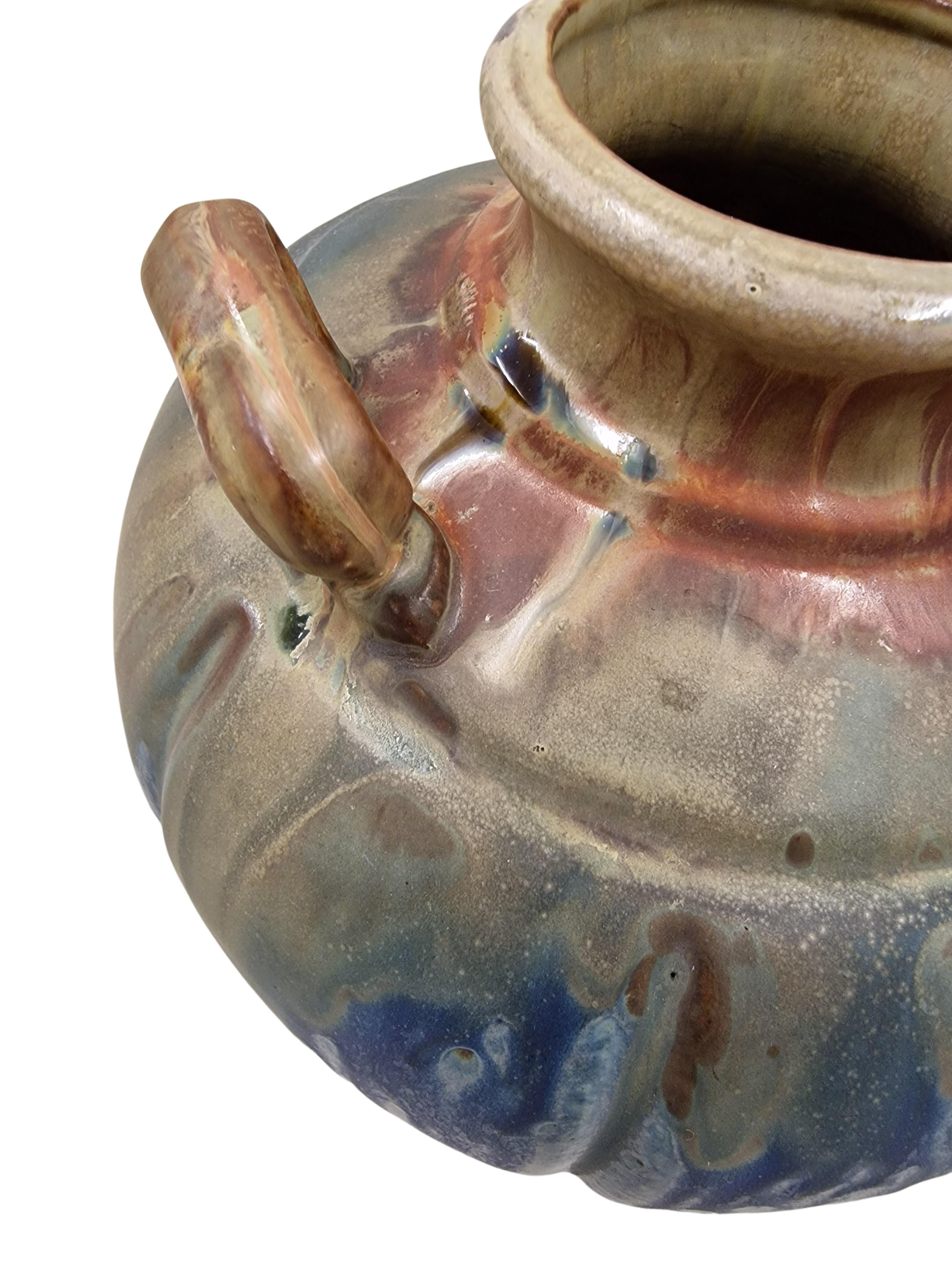 Rare vase, fabriqué en France dans les années 1920, avec une glaçure à ruissellement magistralement exécutée dans des tons de terre. 
La forme compensée du vase présente une sortie ronde supérieure entourée de trois poignées spécialement conçues.