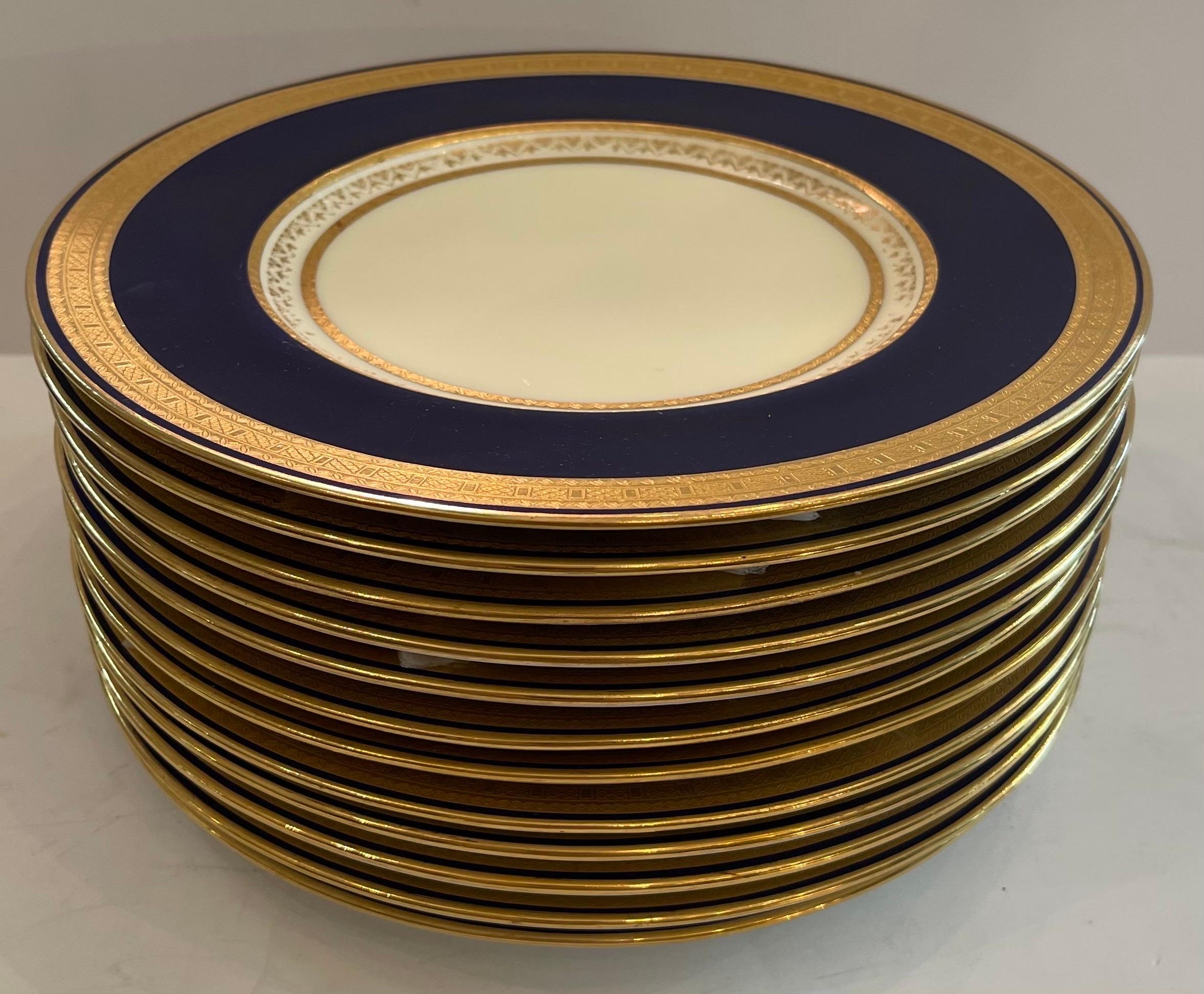 A wonderful classic and elegant set of 12 Minton England bone china dinner plates. This set features a nice deep collar of cobalt blue that is bordered by raised gold on the interior and outer rim. Made of  white porcelain, these plates are in very