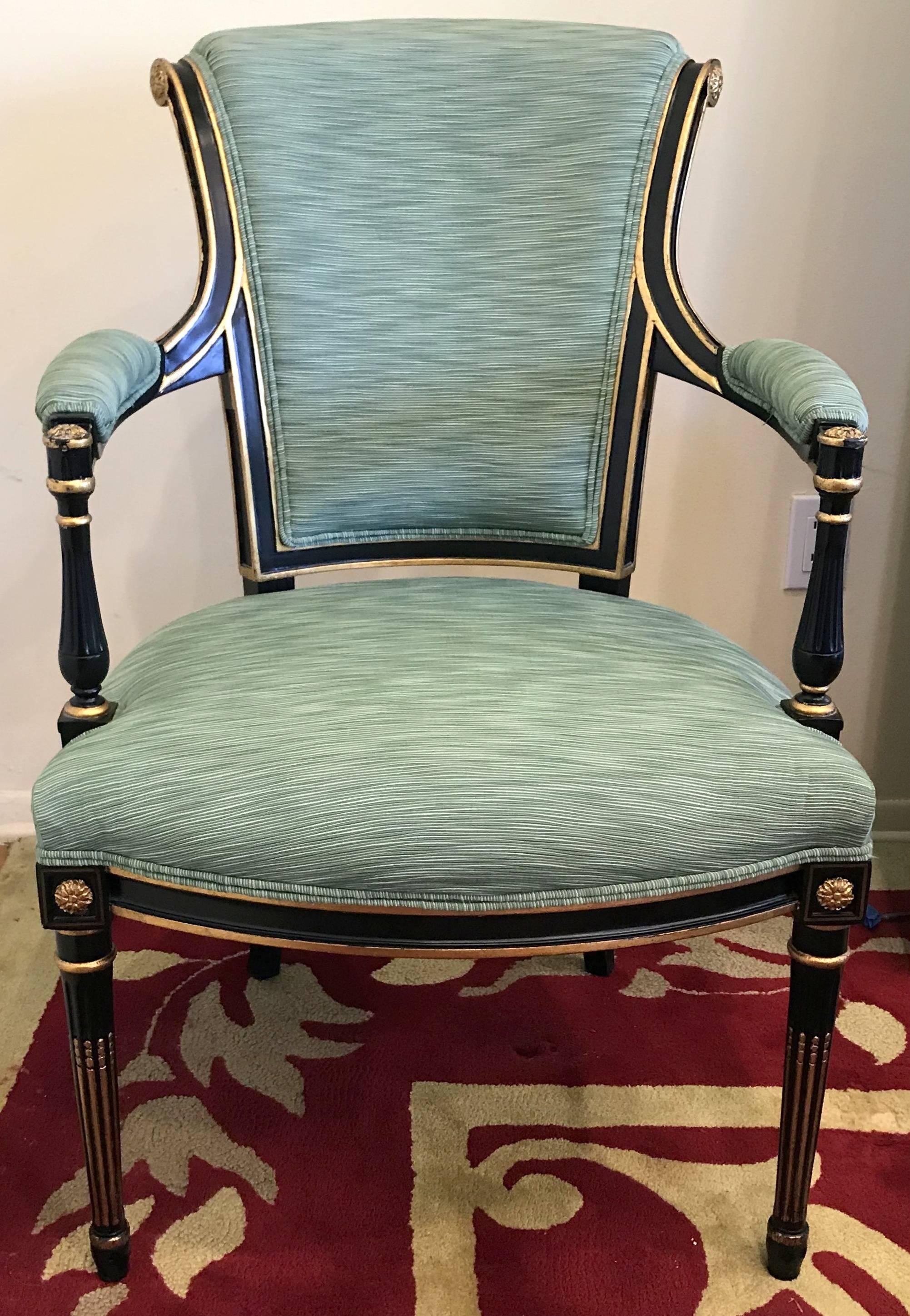 A wonderful set of 12 Regency or neoclassical black lacquered and gold gilt dining room chairs consisting of two armchairs and ten side chairs with green silk upholstery on the front and a red and white stripe on the back side of the chairs, In the