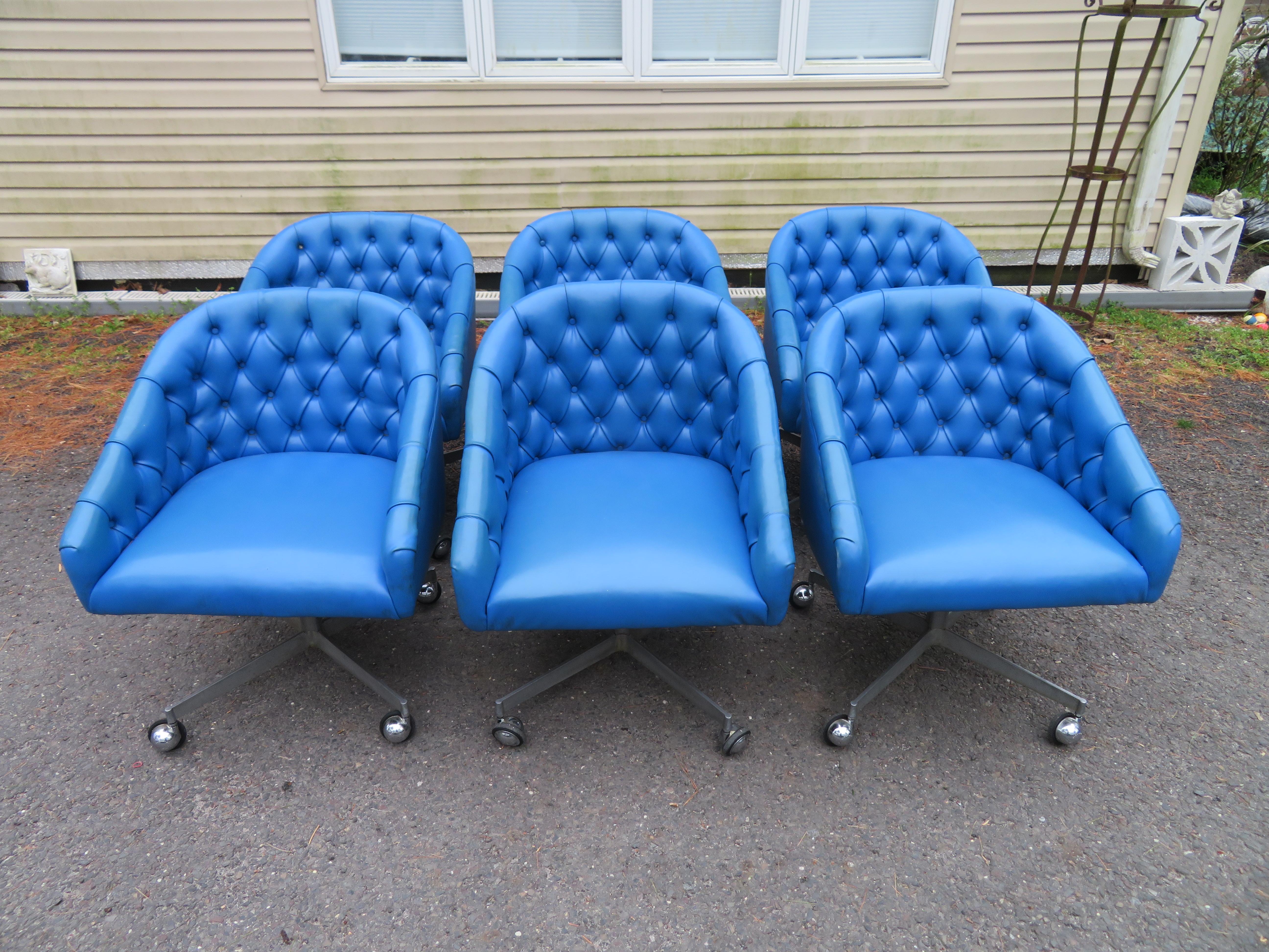 Fabulous set of 6 tufted rolling swivel chairs in race car blue leatherette with cast aluminium star bases and chromed castors. These chairs are in the style of Ward Bennett and retain the original label to the bottom from the Shelby Williams Mfg.