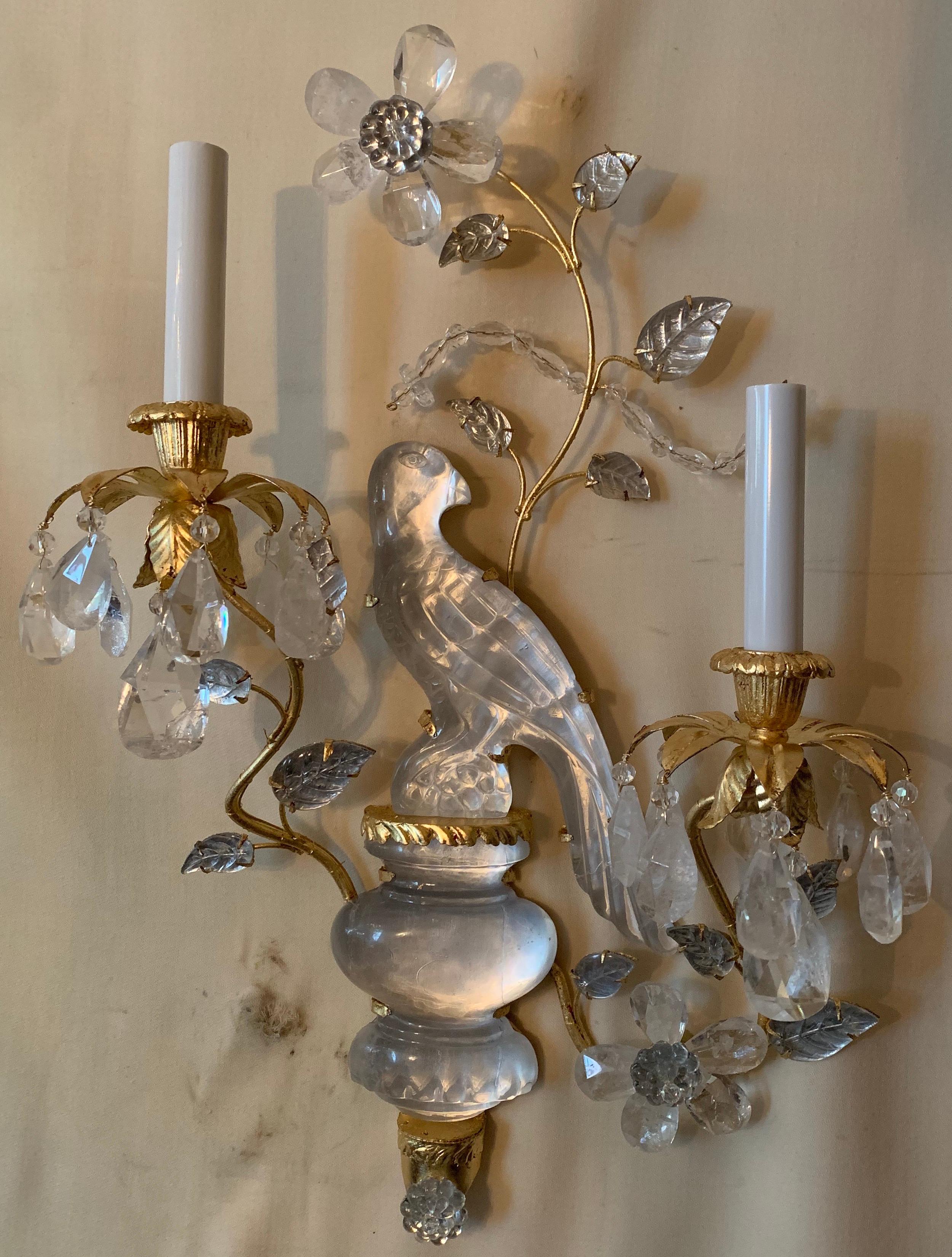 A wonderful pair of Baguès style two-arm rock crystal bird / parrot gold gilt sconces adorned with leaves and flowers, newly rewired with candelabra sockets each pair has a right and left facing bird.
