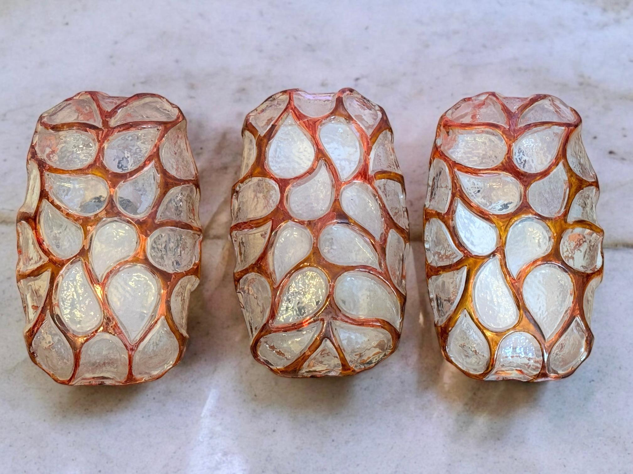 Ensemble de trois petites appliques manufacturées attribuées à Glashütte Limburg. Chaque verre est transparent et monté sur un cadre en métal. Les verres sont décorés de motifs de peau d'animal et de cadres en émail. Chaque luminaire est équipé