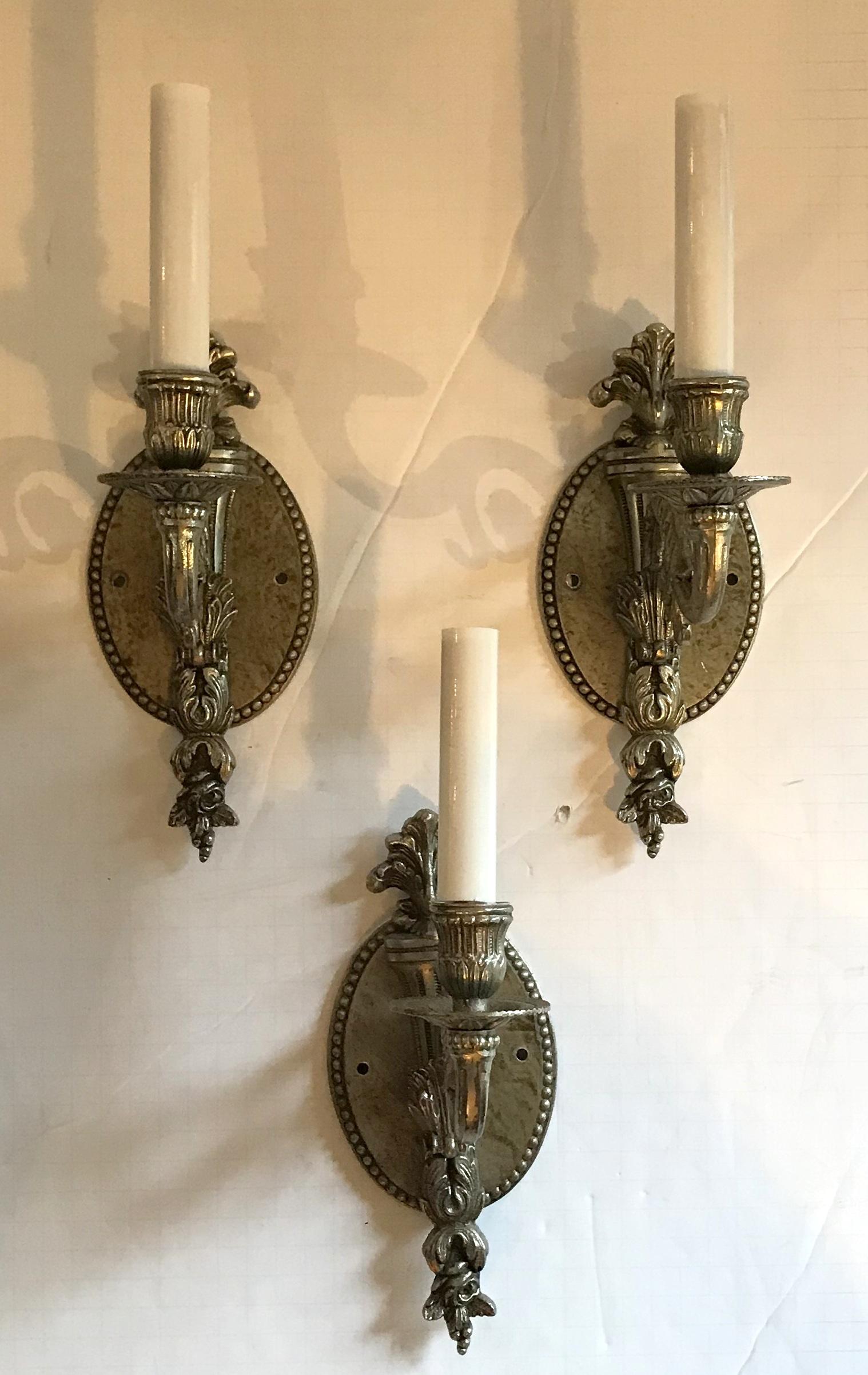 A wonderful set of (3) three French style, antique silver patina bronze single candelabra light torchiere form with filigree and oval back plate neoclassical sconces. UL certified wired and ready to install. In the manner of Caldwell.