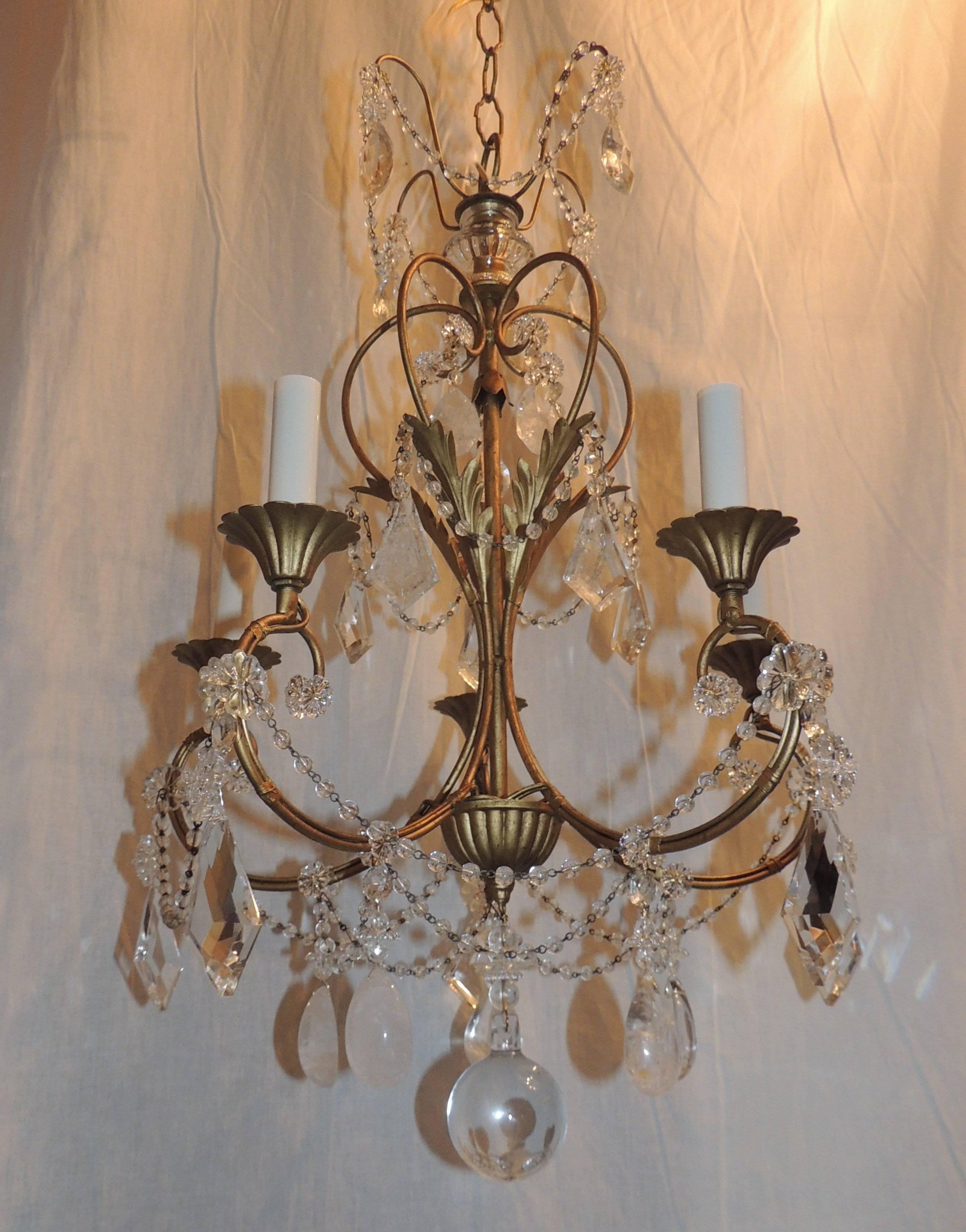 This delicately decorated chandelier has rock crystal prisms and rock and crystal pendants throughout. Draping crystal beads accent the top crown and the lower arms. Beautiful gilt leaves highlight the center and fluted candle cups add to the charm