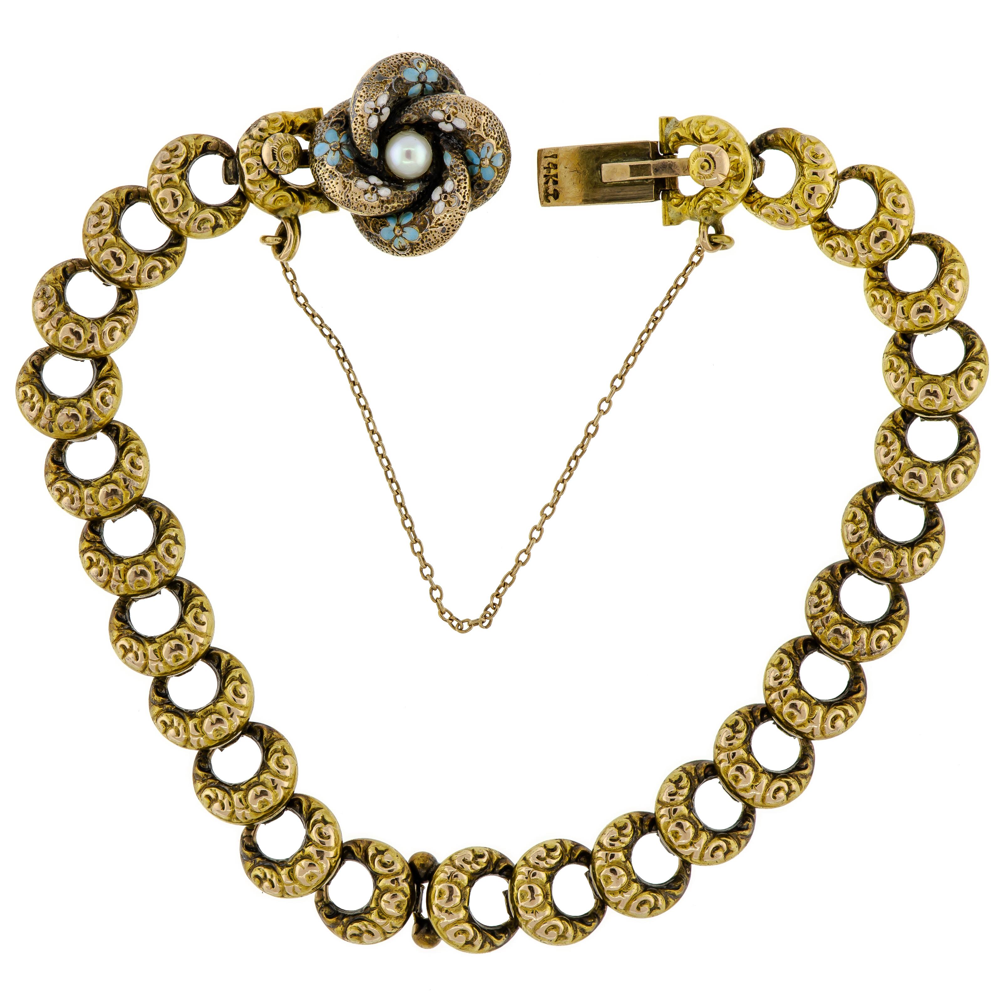 Charming turn-of-the-century love knot, curb link bracelet is made up of crescent-shaped links which are engraved with a lovely design. Handcrafted in 14k yellow gold. The love knot is decorated with blue and white enamel 