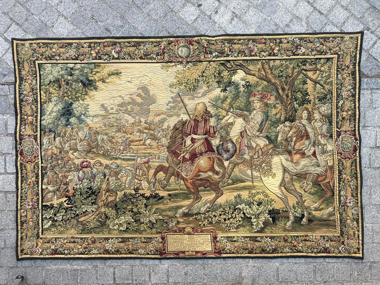 A stunning mid-century French tapestry featuring a captivating battle scene. At the bottom of the tapestry, you'll find an inscription that reads 'Defeat of the Spanish army near the Bruges canal, under the leadership of Marsin, by the troops of