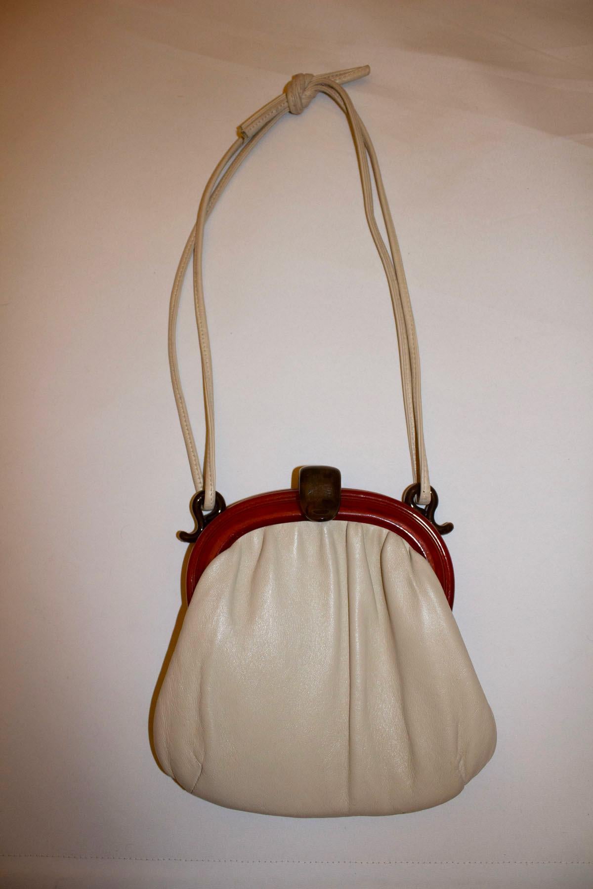 A chic white leather vintage bag with attractive frame and clasp.  The strap could be changed to chain one, or a longer leather on if preferred. Inside there is one pouch pocket . Measurements: Height 9'' x width 9 1/2''