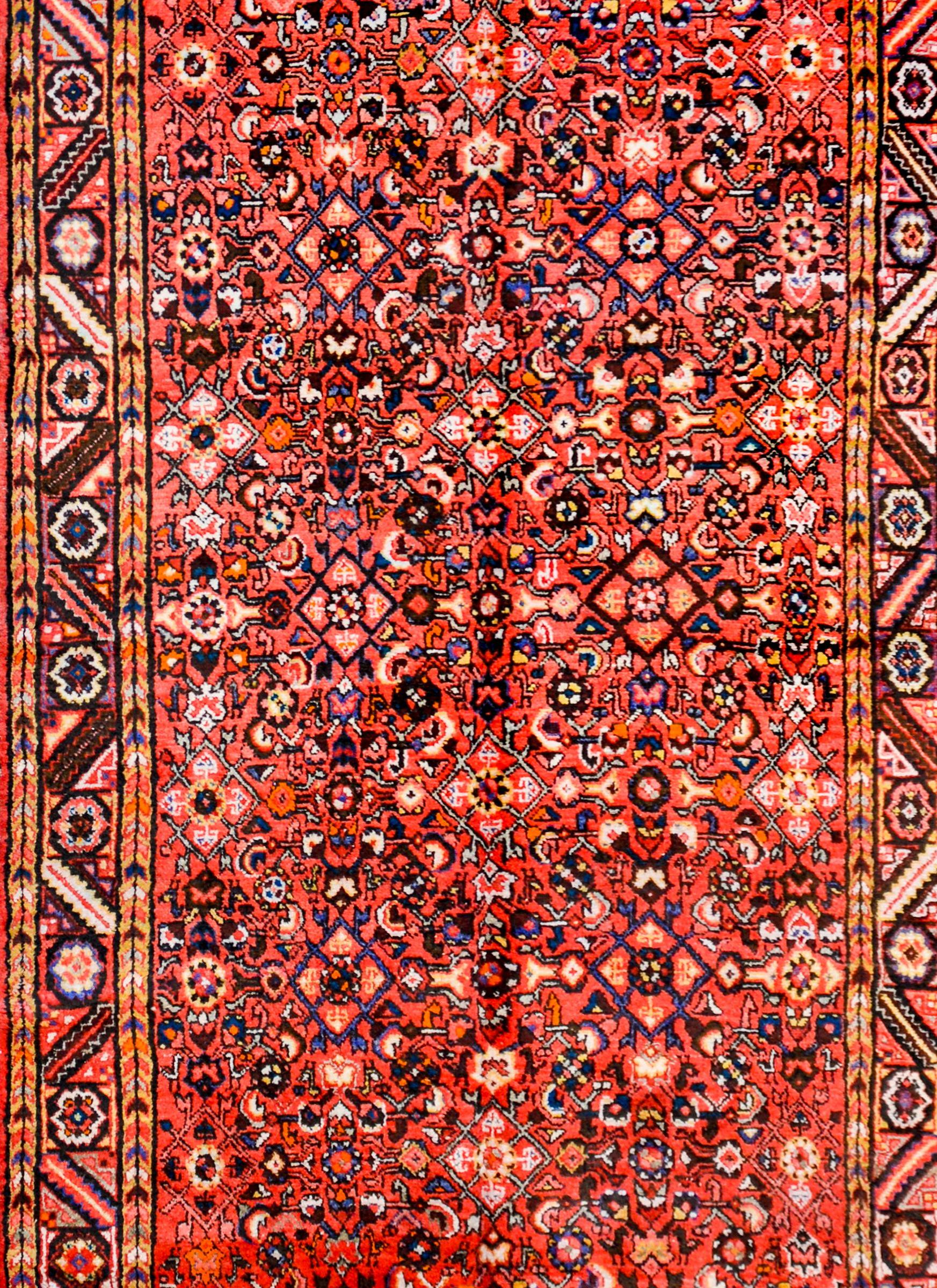 Wonderful vintage mid-20th century Persian Hamadan rug with an densely woven field containing a trellised floral pattern woven in orange, black, indigo, and white colored wool, on a bright crimson colored background. The border is beautiful with a