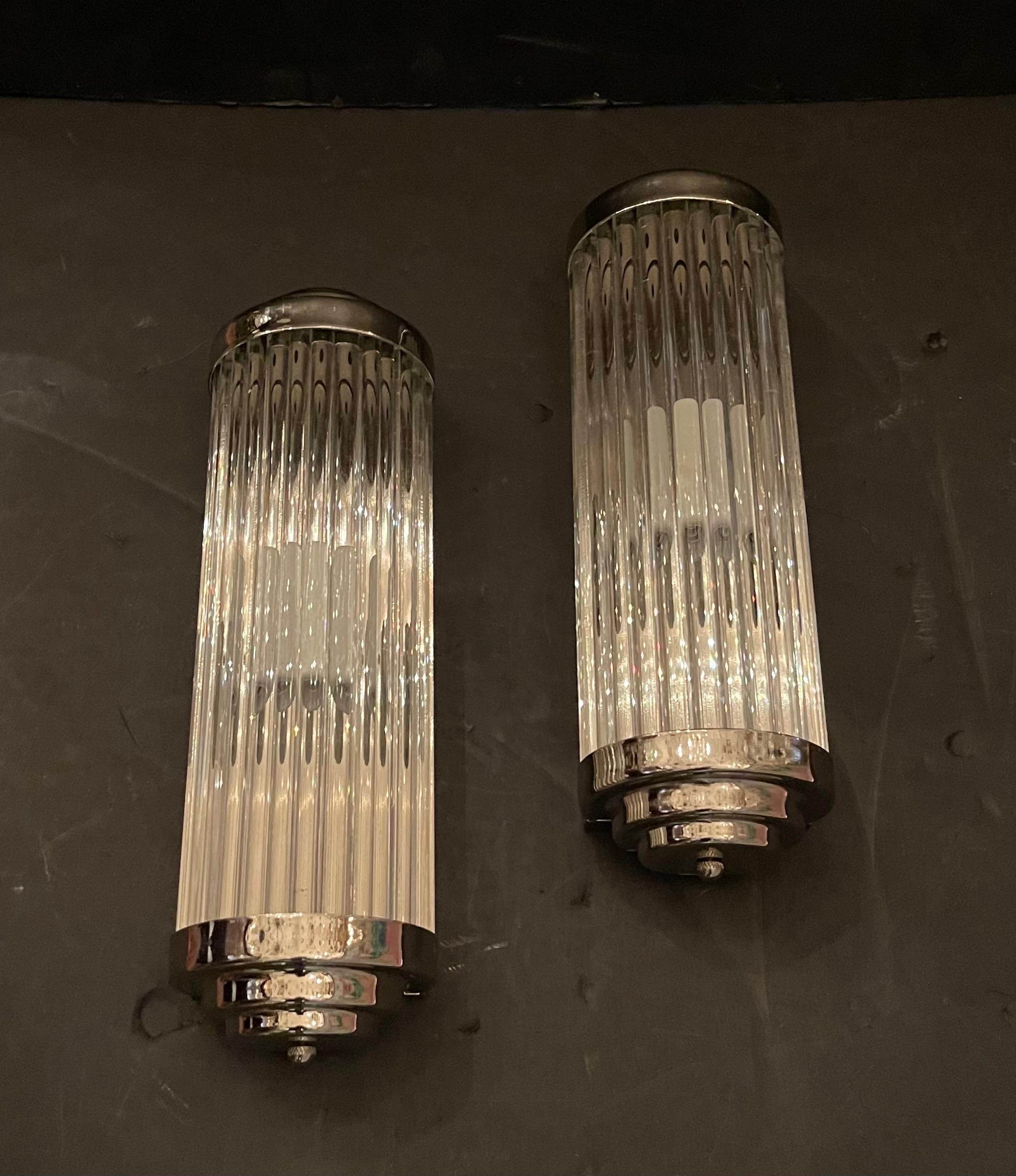 Splendida coppia di lampade da parete vintage di medie dimensioni, placcate in nichel lucido e con asta in vetro, in stile teatro/cinema, che possono essere collocate in un'area umida poiché sono state ricablate con prese in porcellana.

Al momento
