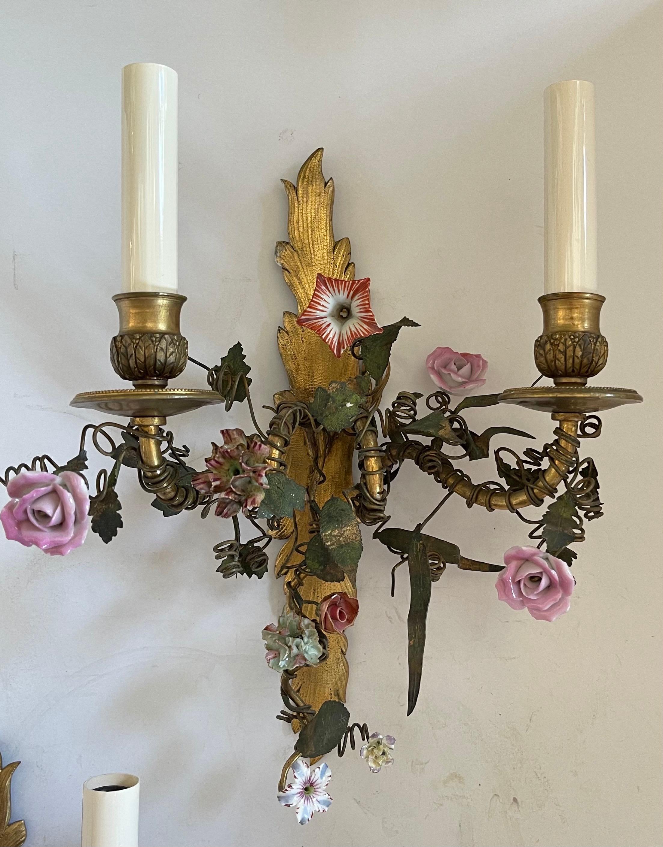 A wonderful pair of french vintage bronze two-arm candelabra sconces rewired with porcelain flowers through out.
